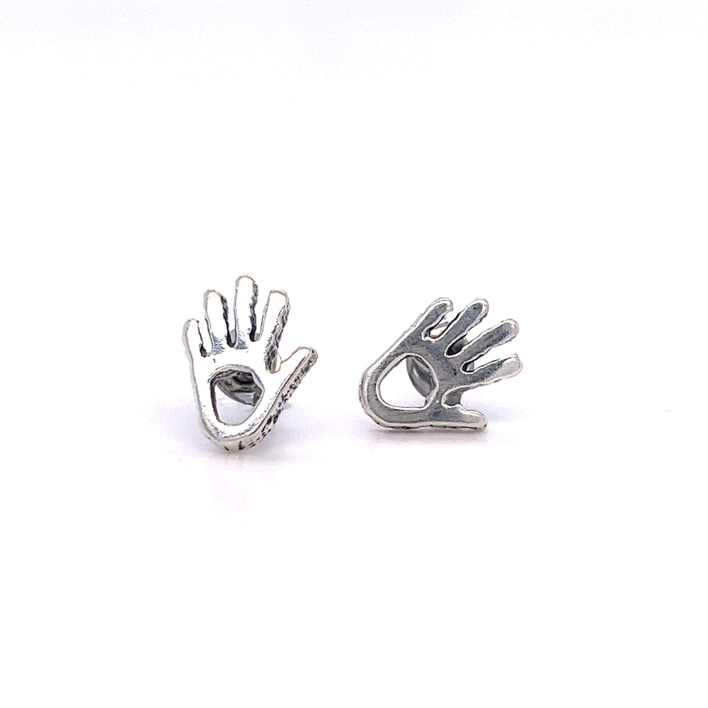 
                  
                    A pair of Super Silver Petroglyph Hand Studs on a white surface, inspired by the hand petroglyphs of the Anasazi people known for their helping and healing abilities.
                  
                
