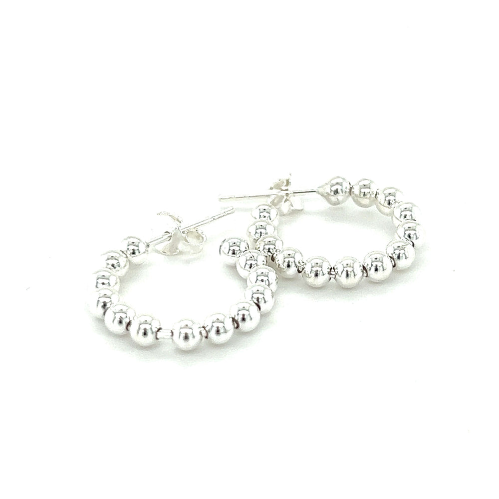 
                  
                    A minimalist pair of Super Silver Delicate Ball Hoops With Post earrings on a white background.
                  
                
