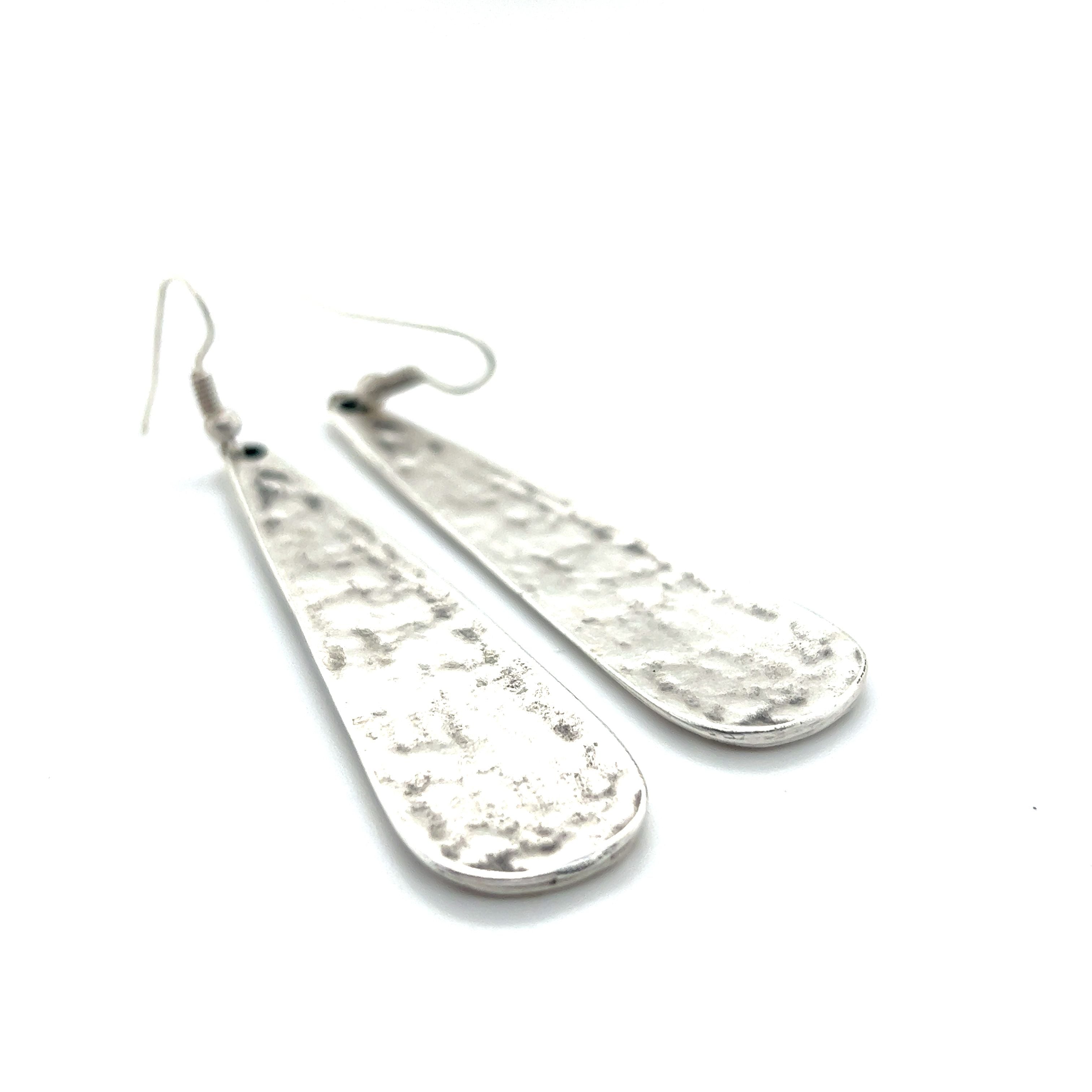 A pair of Super Silver Long Boho Statement Earrings on a white surface.