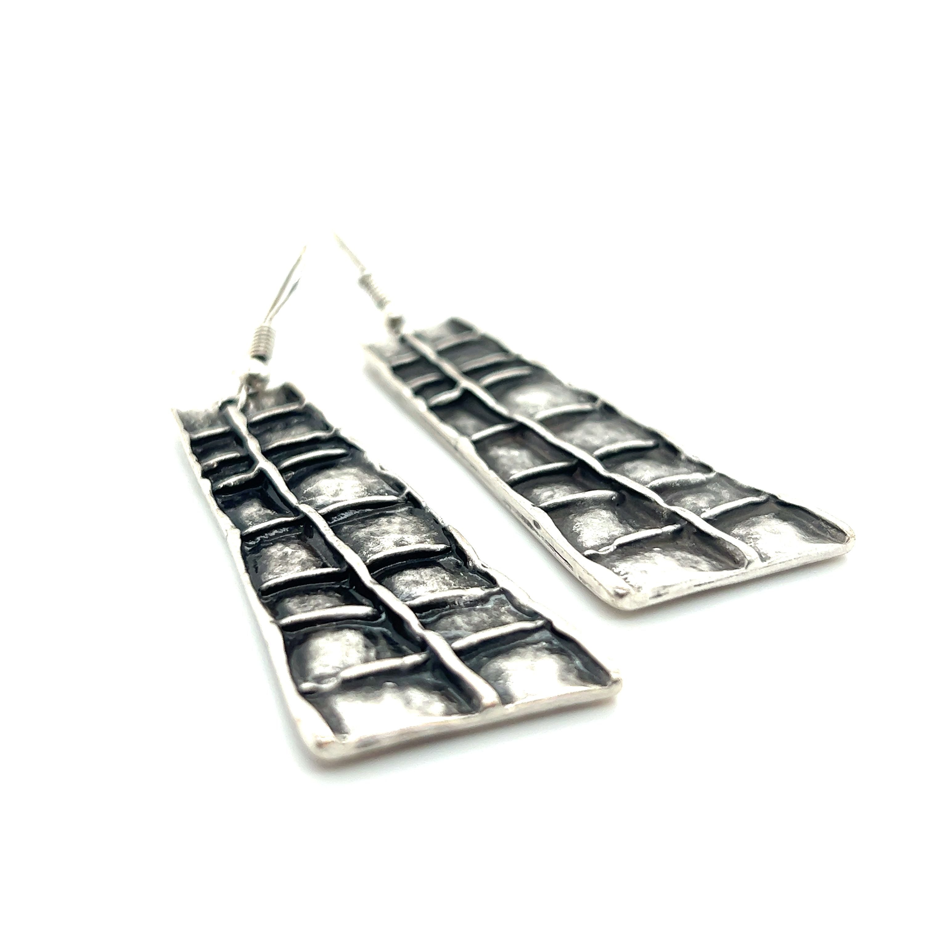 A pair of Super Silver Long Boho Statement Earrings with a pattern on them.