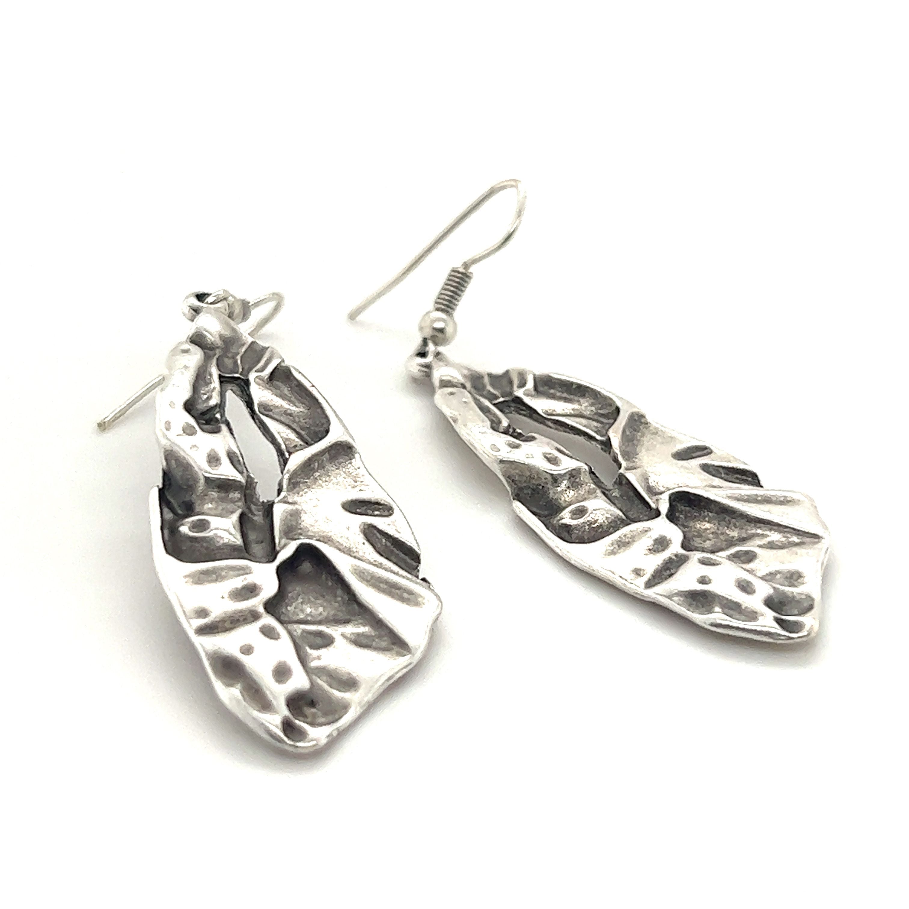 A pair of Super Silver Triangular Boho Statement Earrings adorned with delicate leaves, perfect for an urban boho jewelry collection. Made from high-quality Zamak, these earrings are an exquisite addition to any wardrobe.