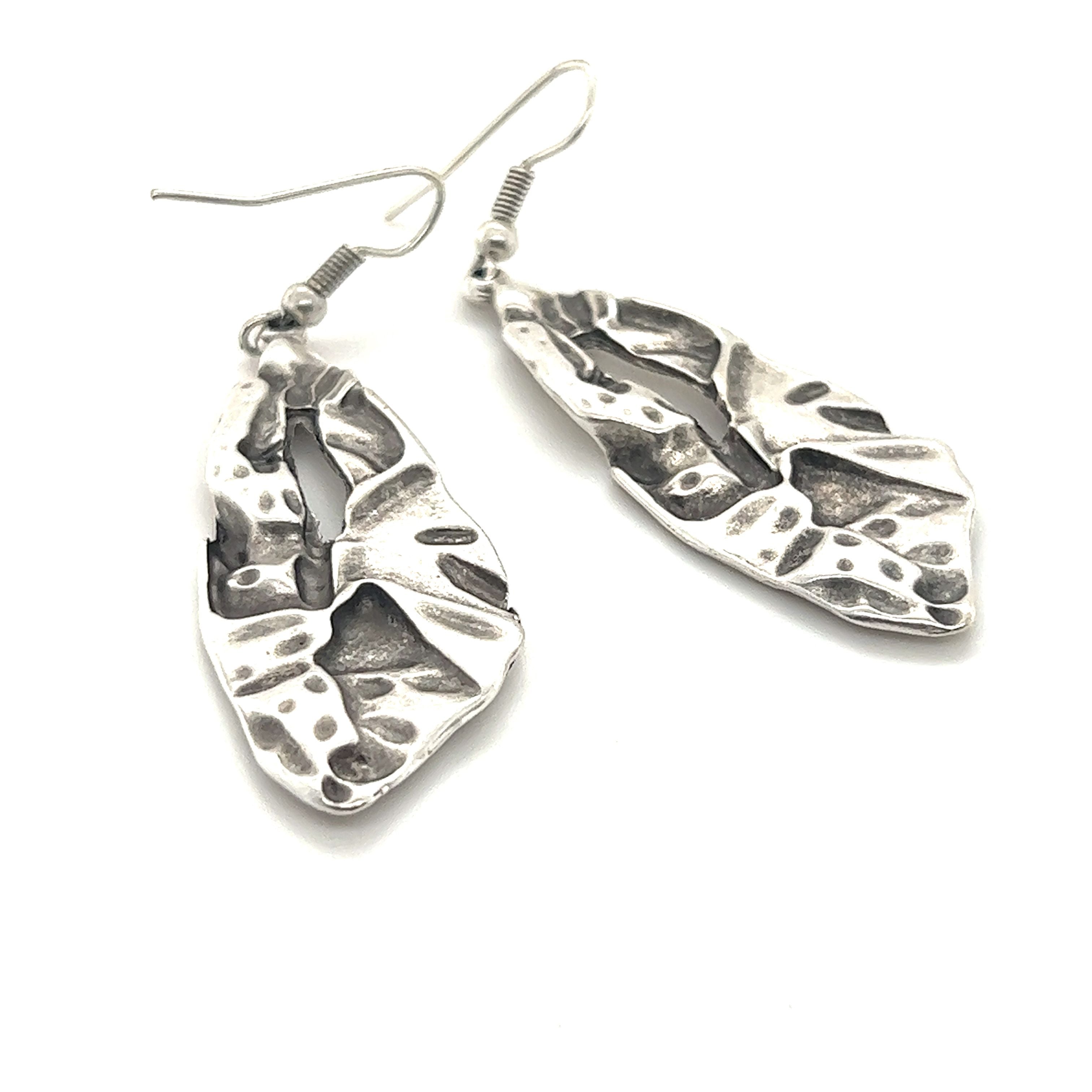 A pair of Super Silver Triangular Boho Statement Earrings with leaves on them.