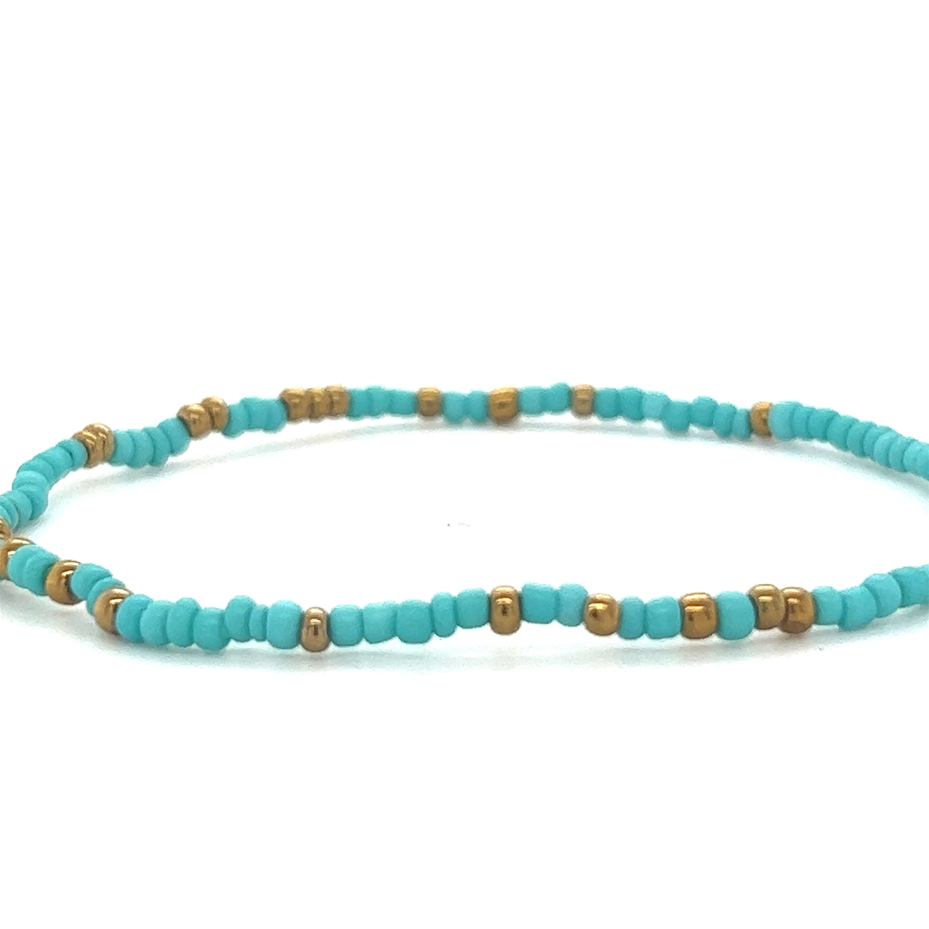 A Dainty Beaded Bracelet by Super Silver featuring turquoise and gold colors on a white background.