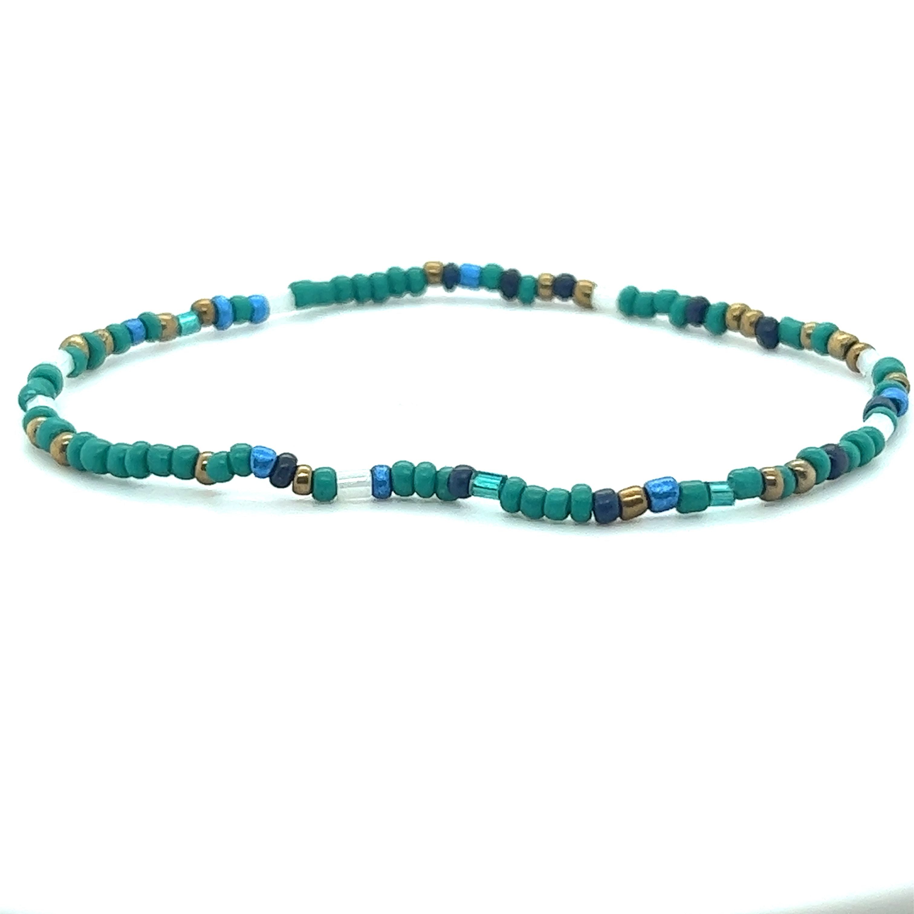 A Super Silver Dainty Beaded Bracelet with a pop of blue on a white surface.