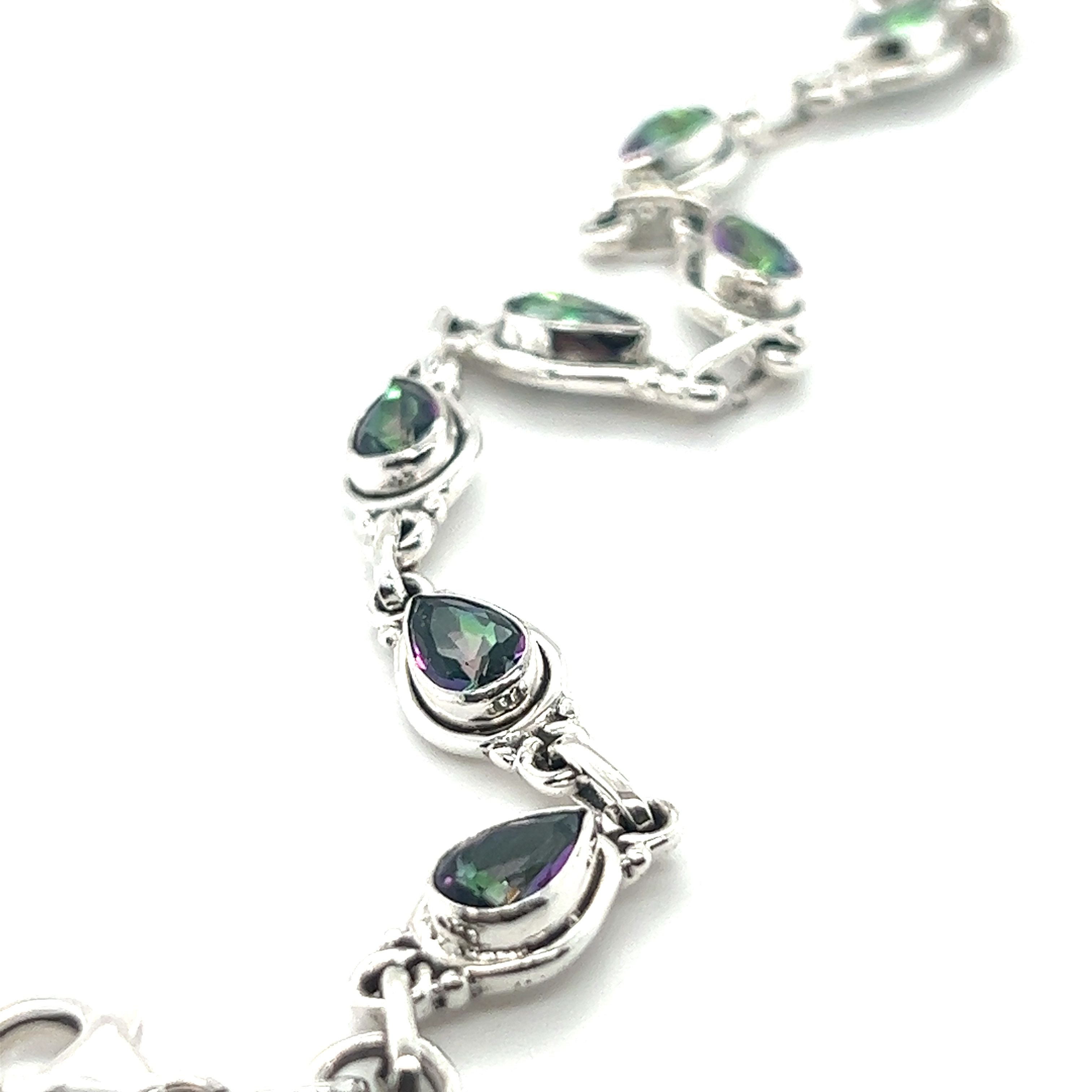 Close-up of a sterling silver bracelet featuring a series of teardrop-shaped settings, each encasing a captivating Rainbow Topaz Bordered Teardrop Bracelet.