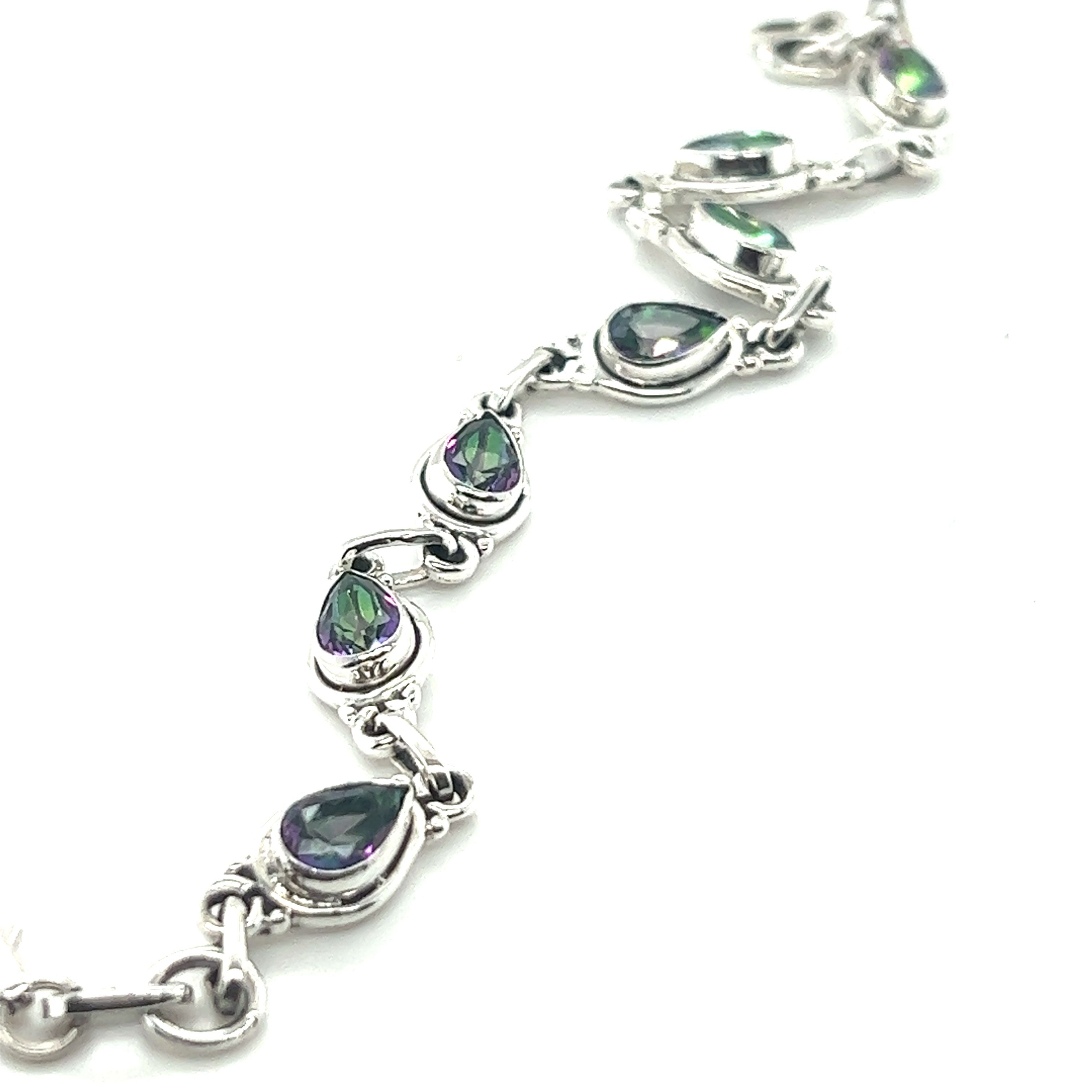 A sterling silver bracelet with multiple pear-shaped, iridescent gemstones set in individual links, arranged in a serpentine pattern. This stunning Rainbow Topaz Bordered Teardrop Bracelet shimmers with captivating hues, making it a true statement piece.