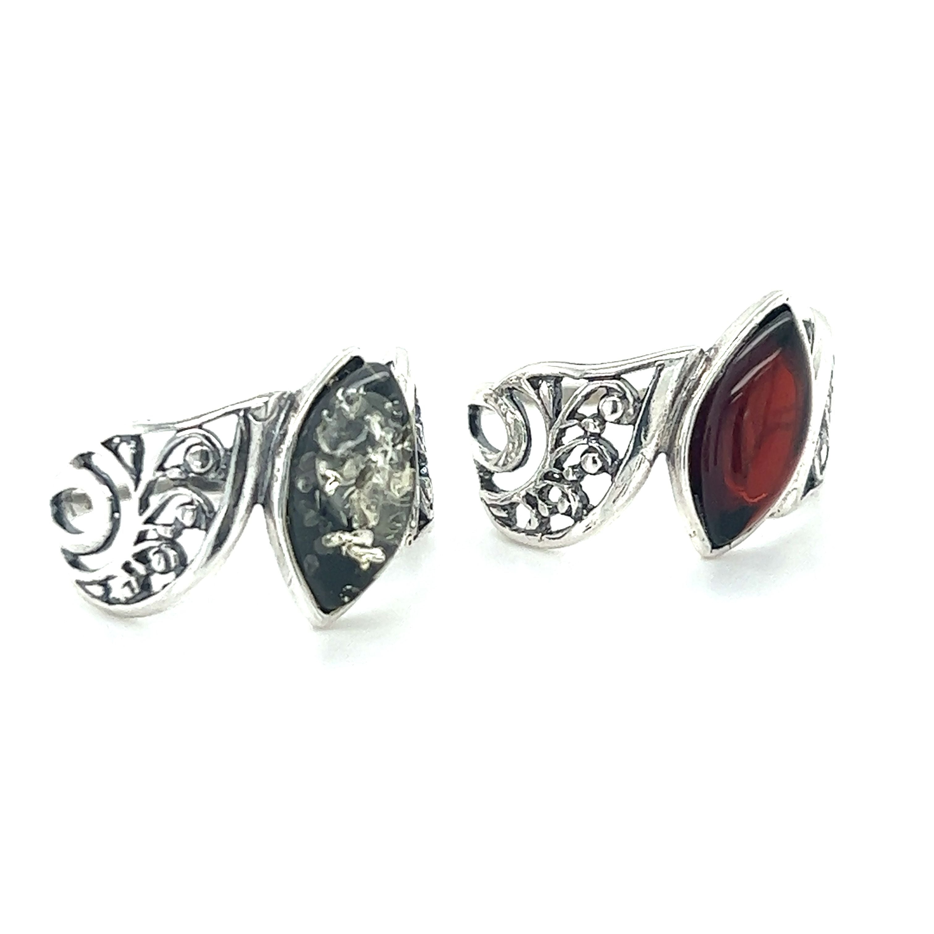 A pair of Super Silver Wide Filigree Band Baltic Amber Rings adorned with red and black stones.