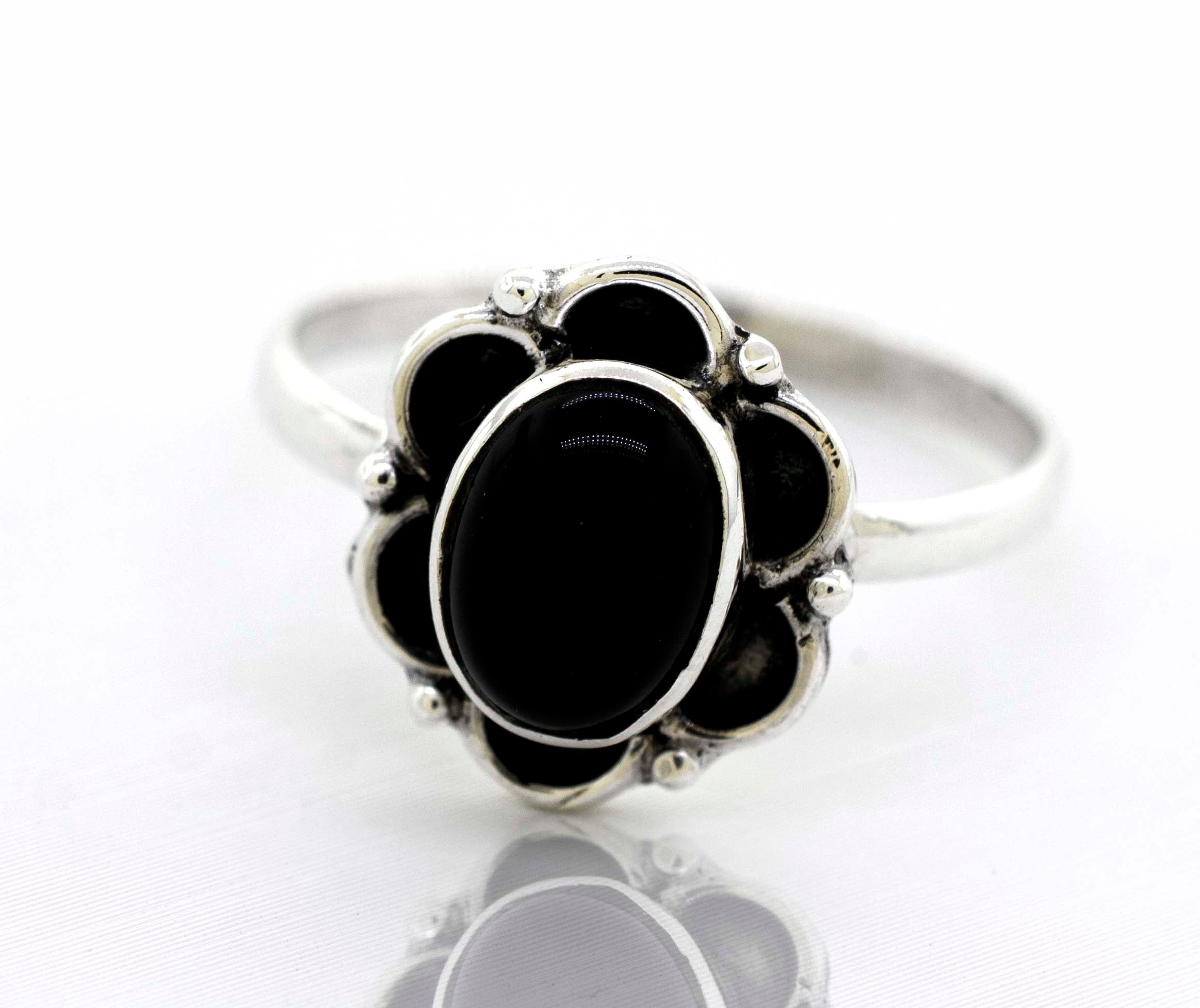 A delicate Super Silver Gemstone Ring With Oxidized Flower Design with a central black onyx gemstone.
