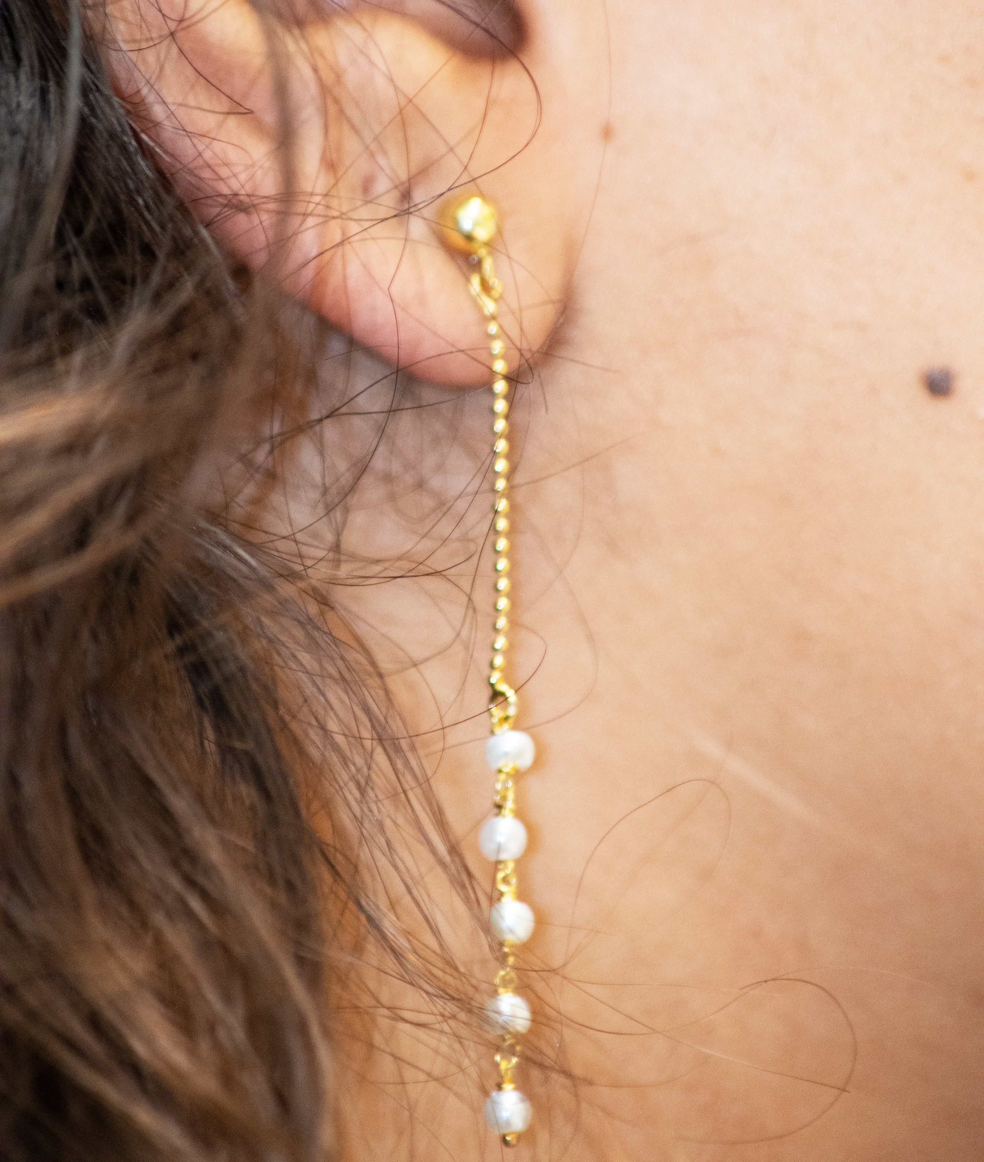 A close up of a woman's ear with a Super Silver 22 Karat Gold chain and Gold Plated Pearl Earrings.