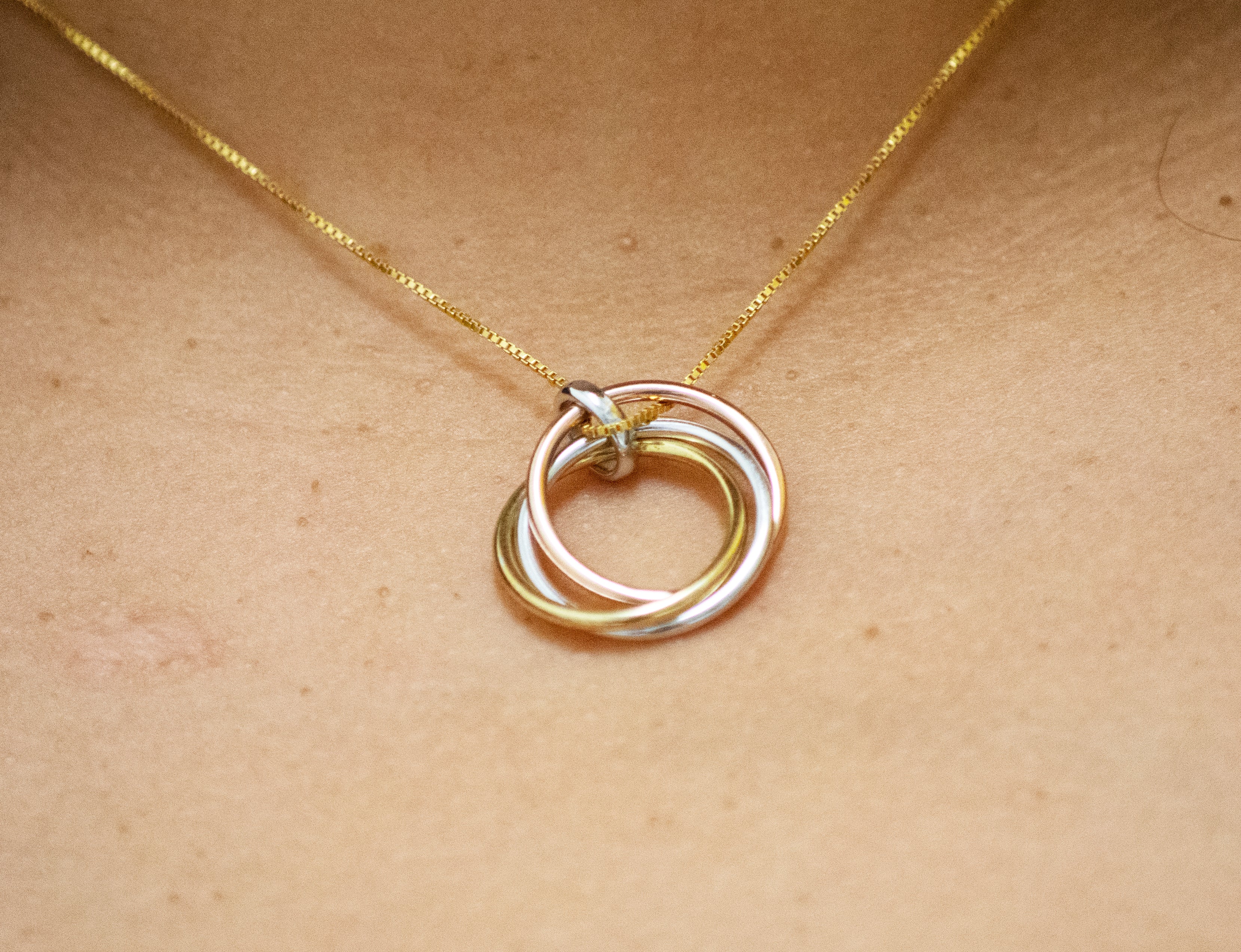 A woman wearing a Simple and Elegant Gold and Rose Gold Plated Pendant with a three ring pendant from Super Silver.