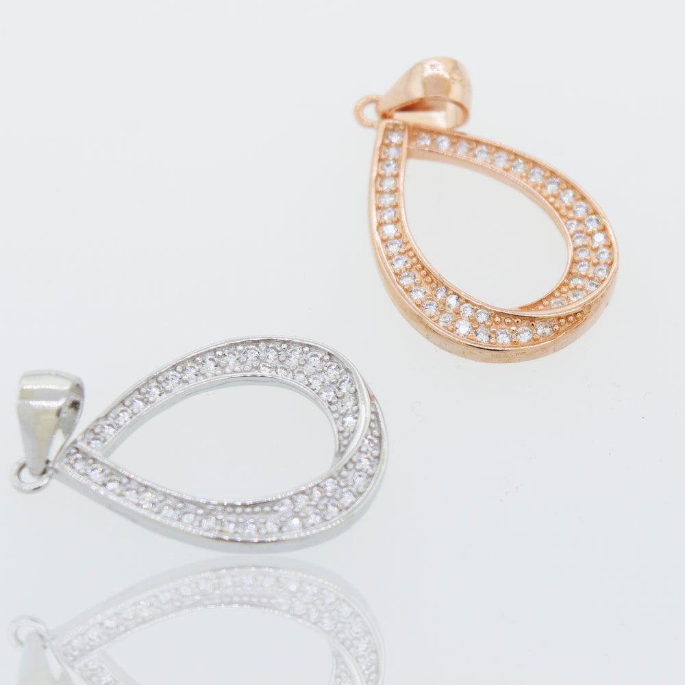 Two Teardrop Shape Cubic Zirconia Pendants, one in gold and one in diamond, displayed elegantly on a white surface.