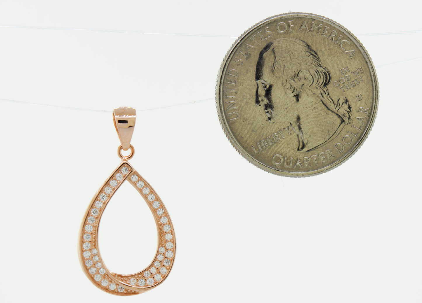 A Teardrop Shape Cubic Zirconia Pendant with a rose gold coin next to it.