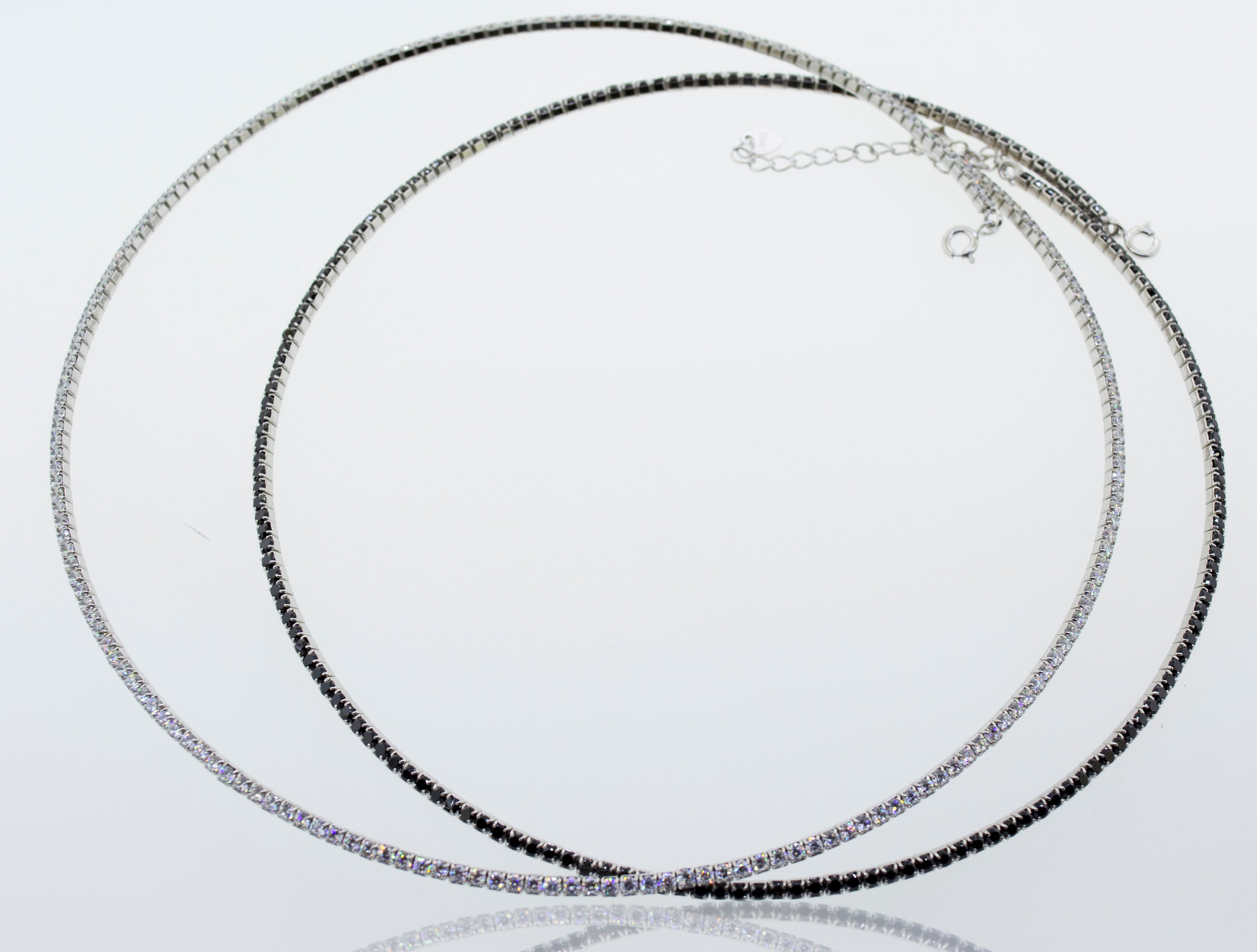 A pair of Super Silver cubic zirconia tennis necklaces with cubic zirconia stones on a white surface.