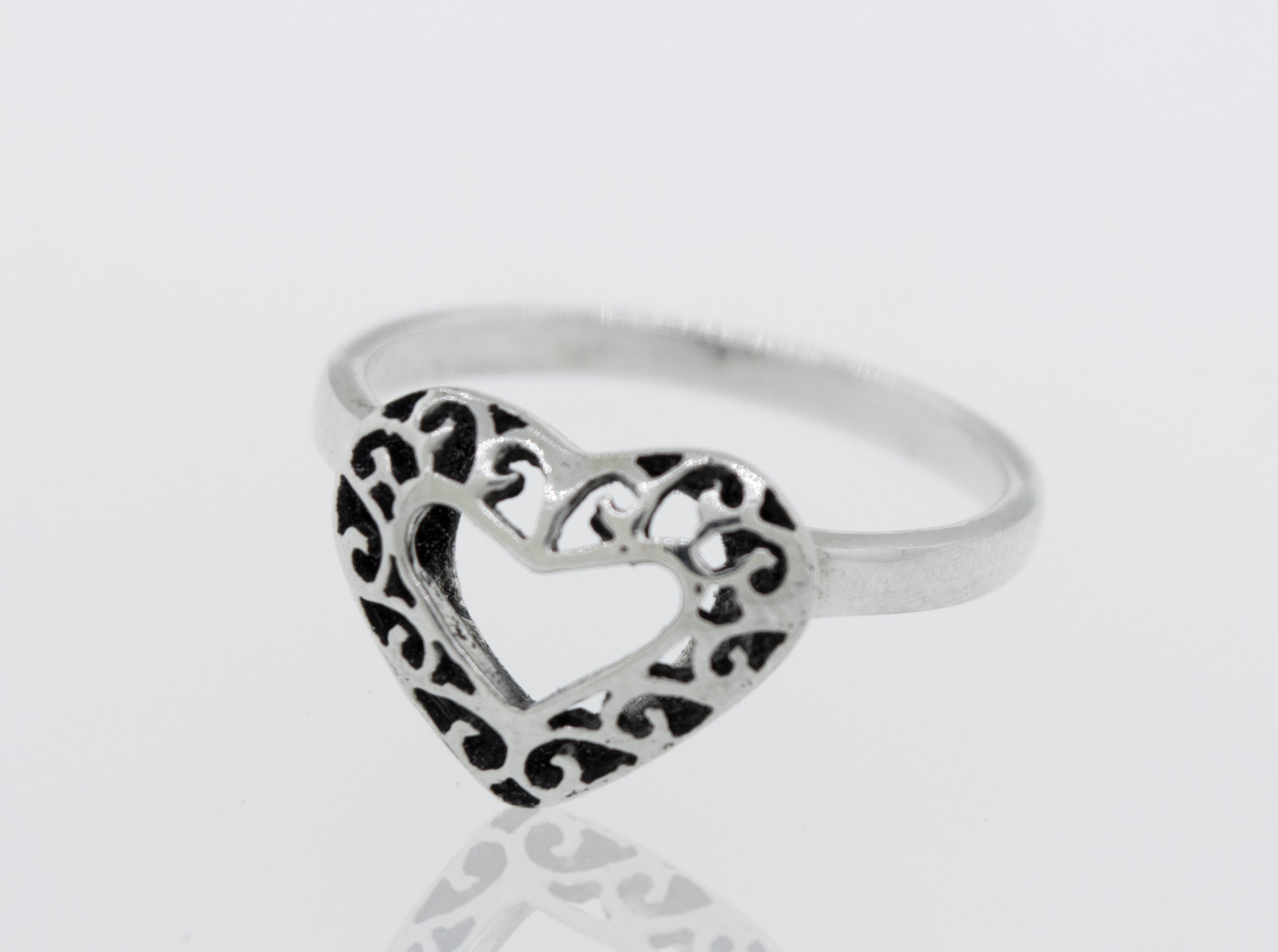 A minimalist Heart Shaped Ring with Filigree Detailing on a white surface.
