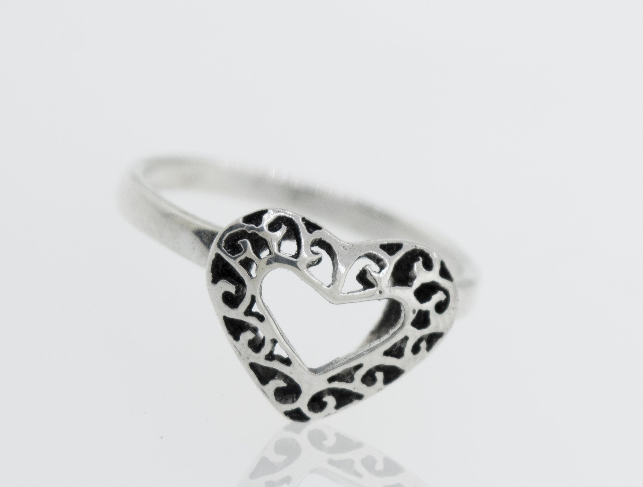 A minimalist Heart Shaped Ring with Filigree Detailing in the shape of a heart resting on a white surface, representing pure love.