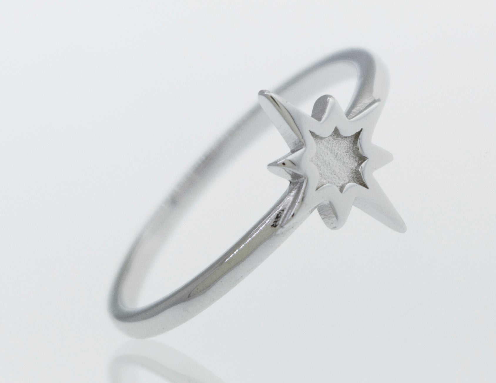 A Super Silver Twinkle Star Ring twinkles on a white surface.