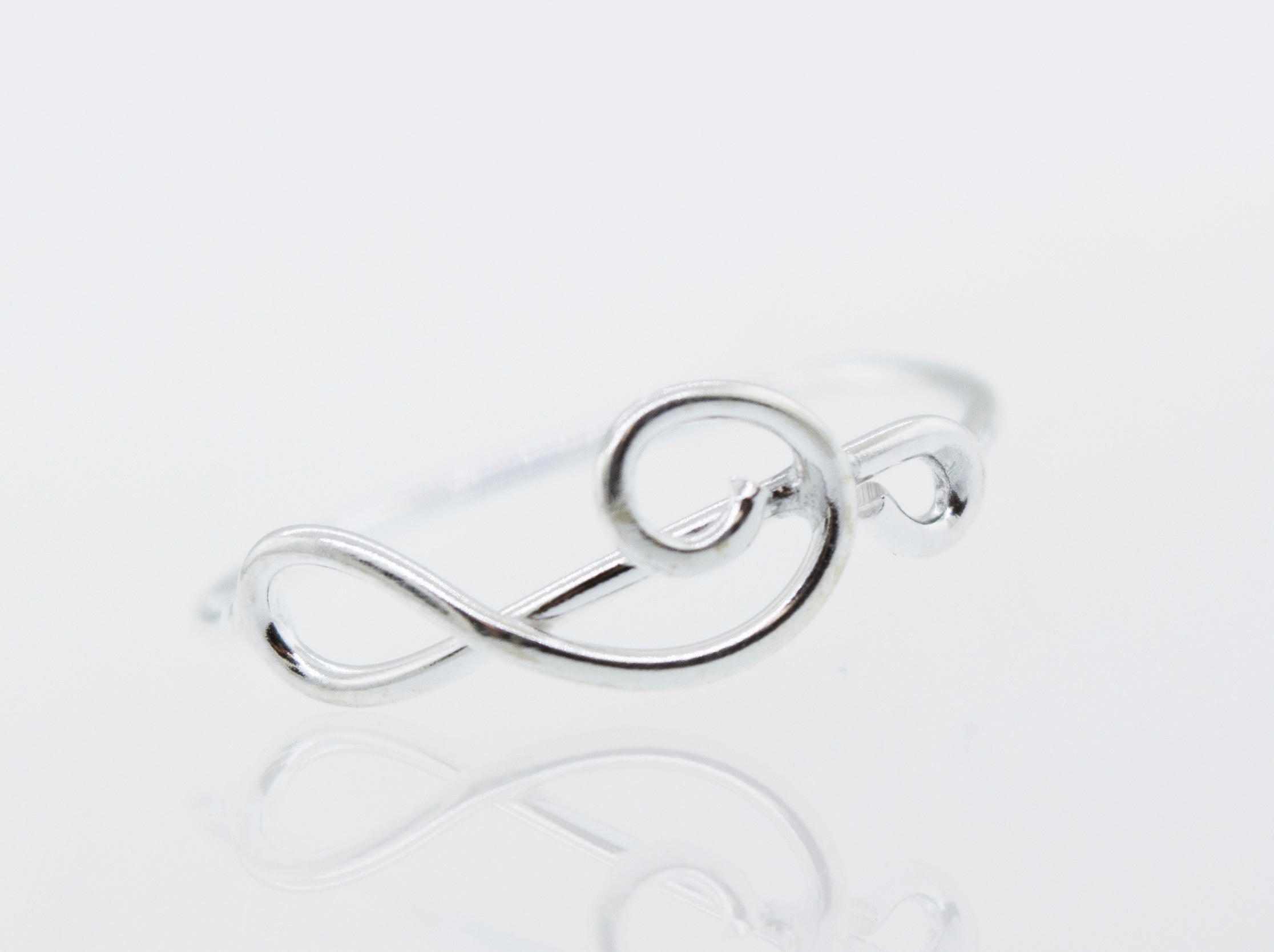 A Super Silver Horizontal Treble Clef Ring with a treble clef design on a high polish white surface.