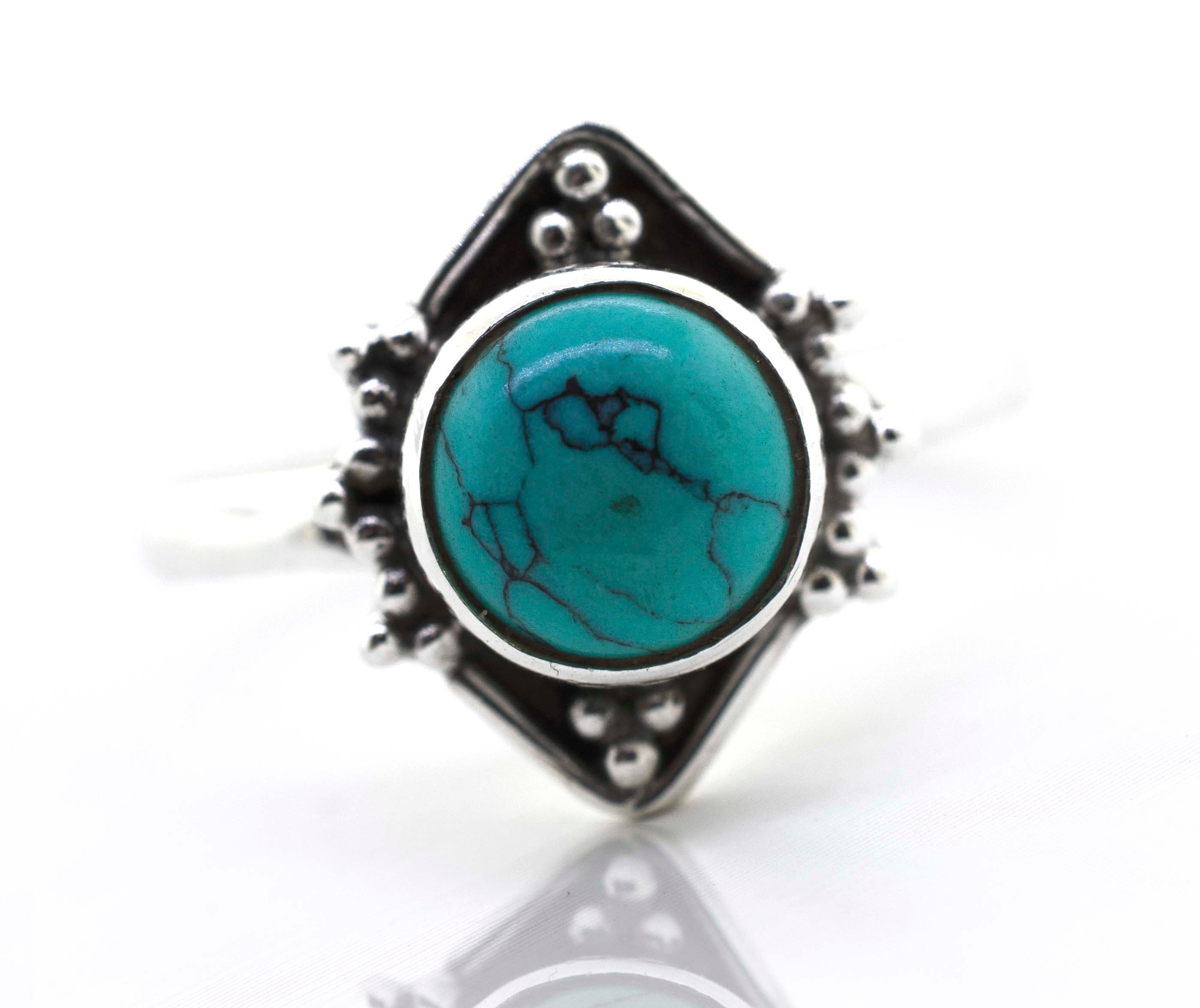 A Super Silver round gemstone ring with oxidized diamond shape pattern set with a stunning turquoise gemstone.