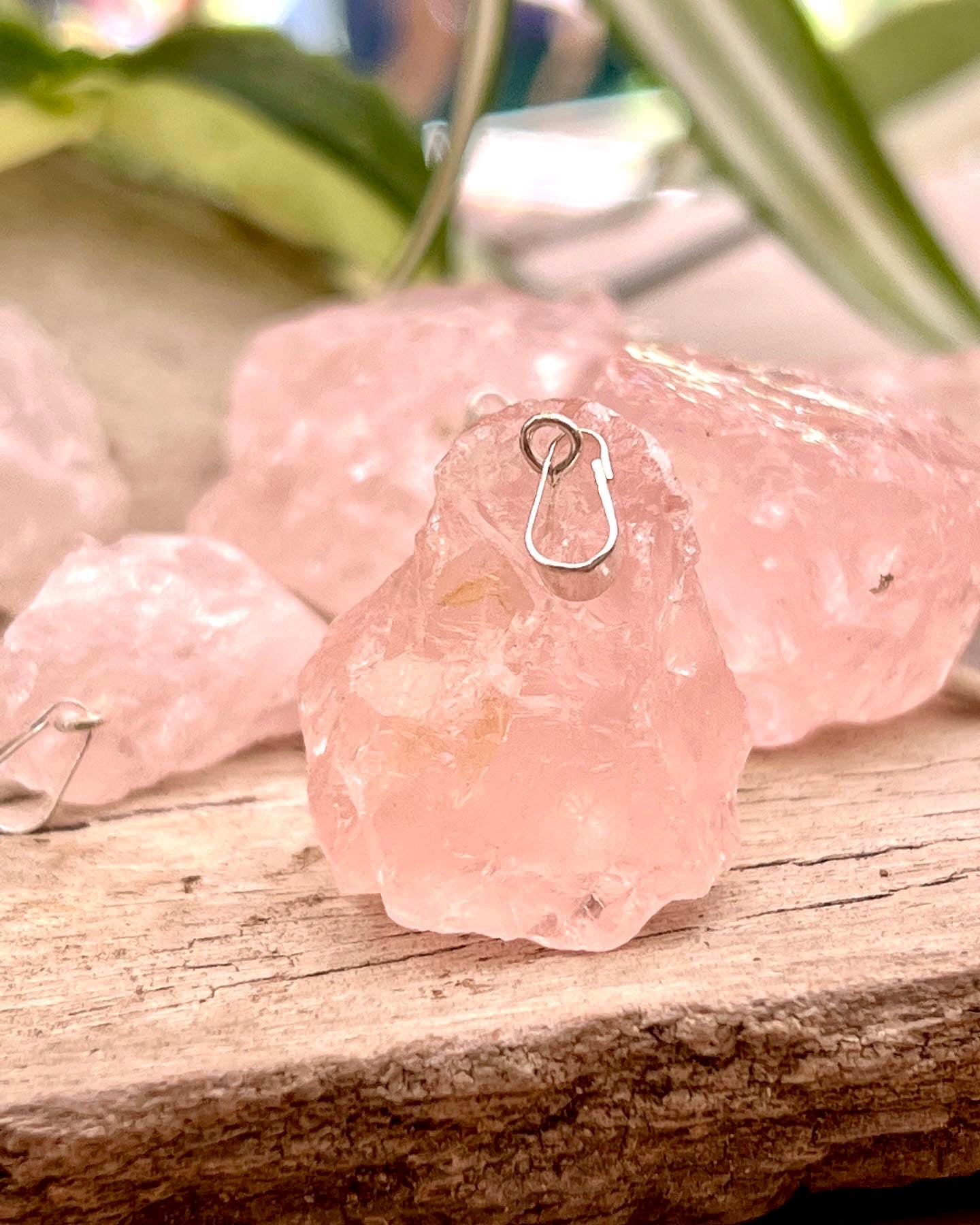 A bunch of pink Super Silver Raw Crystal Pendants on a wooden table.