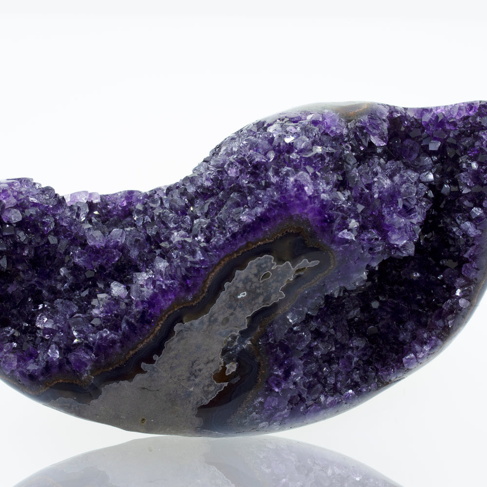 An Egg Shaped Amethyst Geode stone on a white surface.