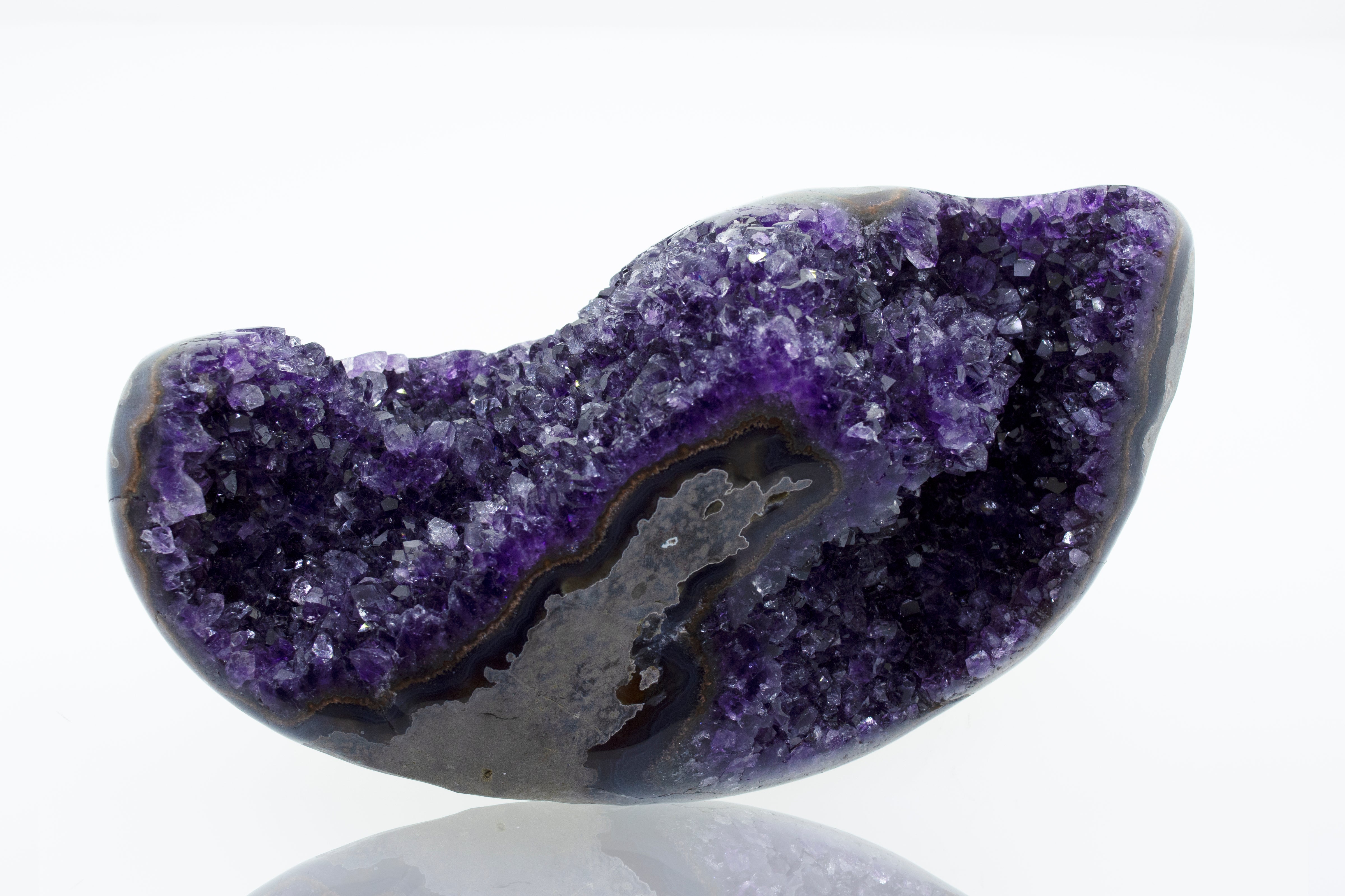 An Egg Shaped Amethyst Geode stone on a white surface.