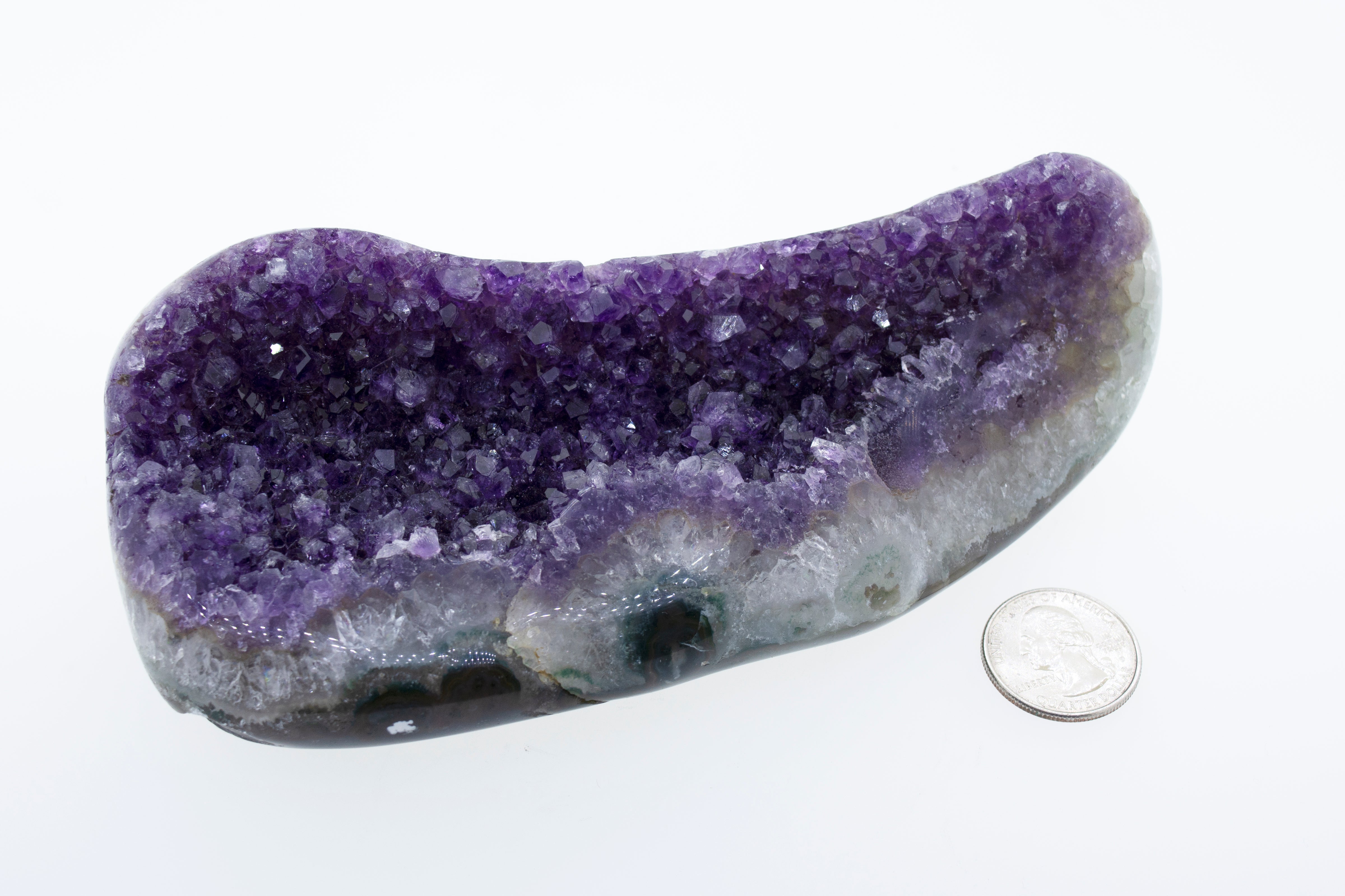 An Oval Shaped Amethyst Geode decor next to a dime.