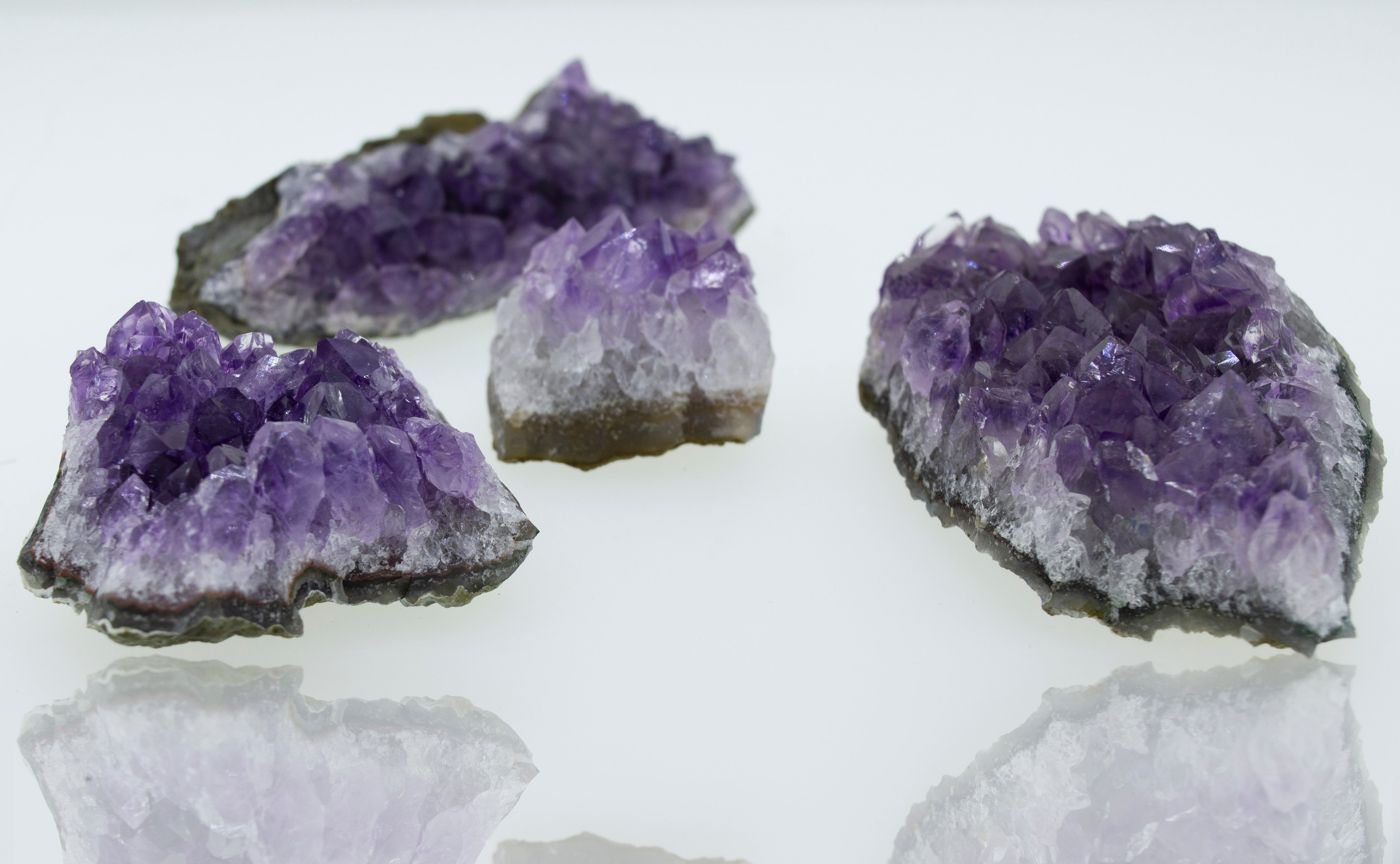 Three pieces of Amethyst Geodes in Varying Sizes, perfect for boho decor, placed on a white surface.