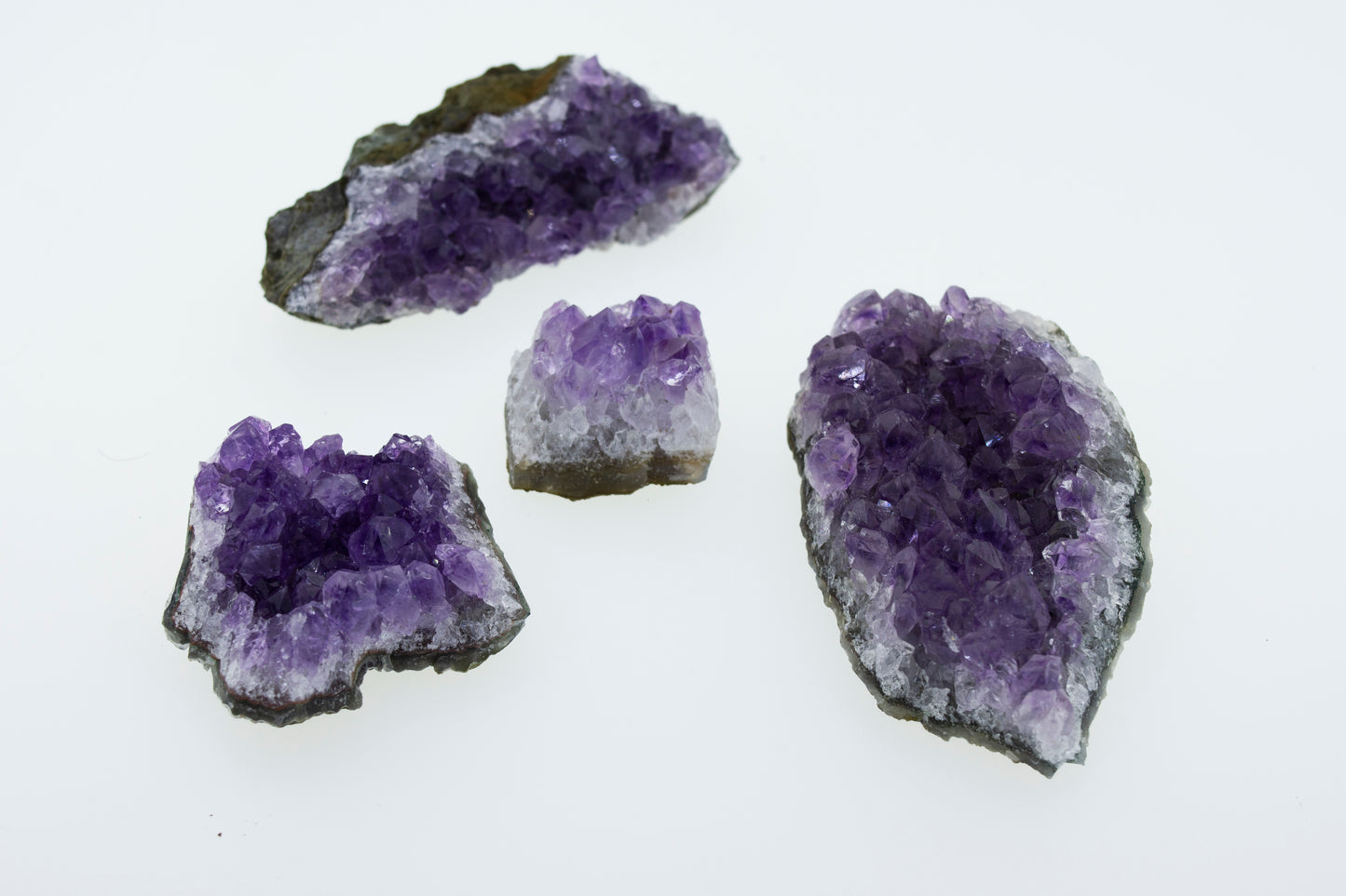 Three pieces of Amethyst Geodes in Varying Sizes on a white surface.