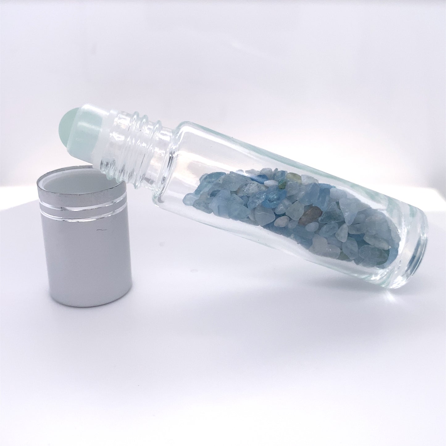 
                  
                    A glass bottle with blue crystals and a tin can next to it, perfect for self care relaxation or Stone Essential Oil Roller storage.
                  
                
