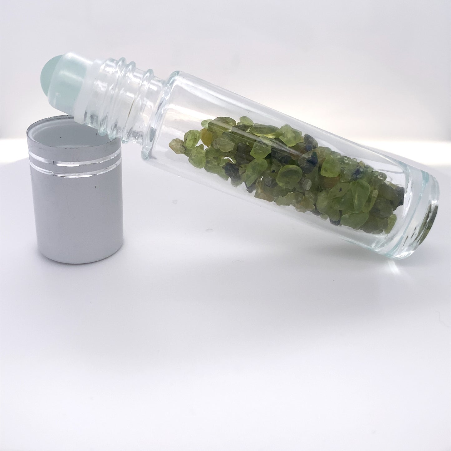 
                  
                    A glass bottle filled with beauty-enhancing green leaves, accompanied by a Stone Essential Oil Roller.
                  
                