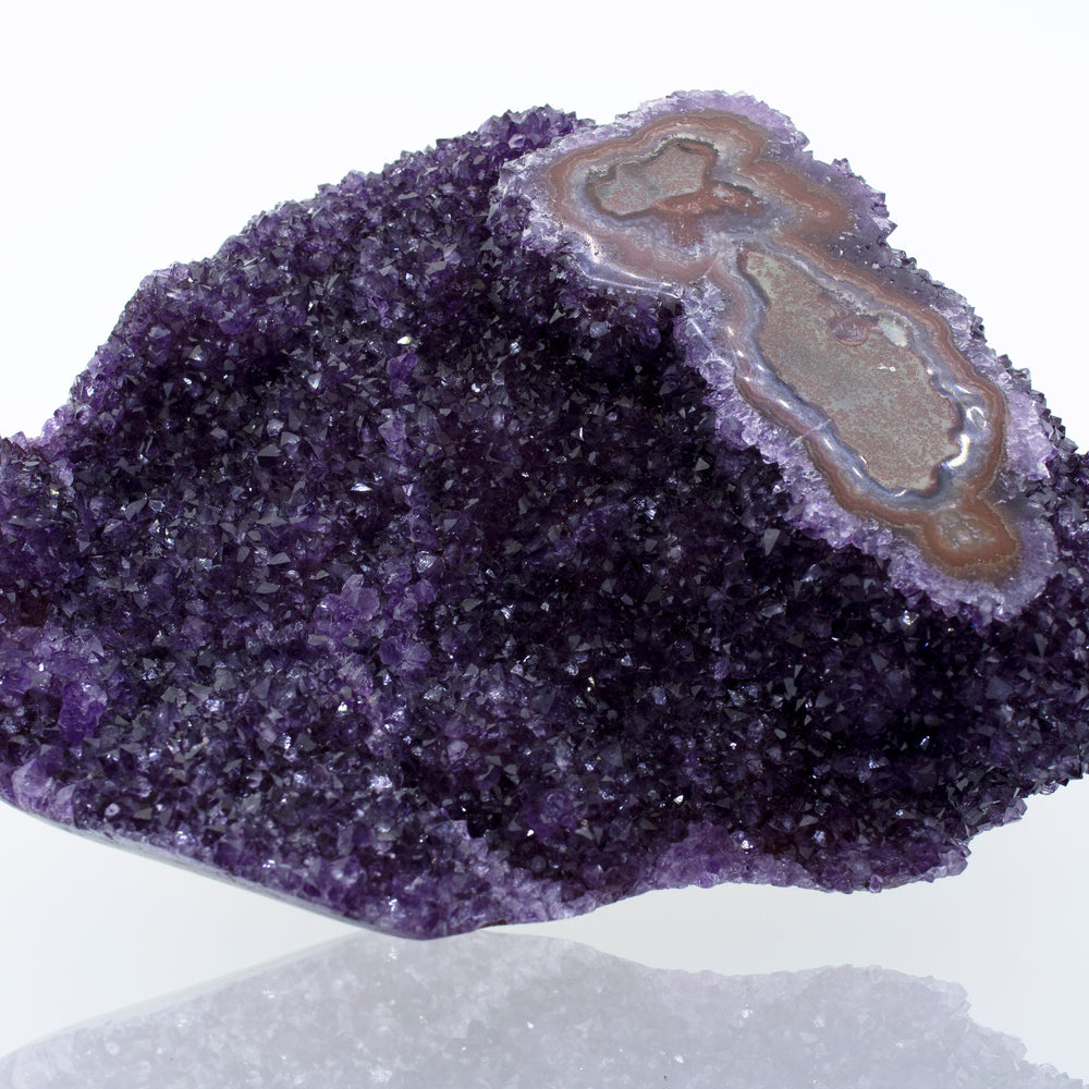 A beautiful Freeform Amethyst Geode decor featuring a purple amethyst crystal on a white surface.