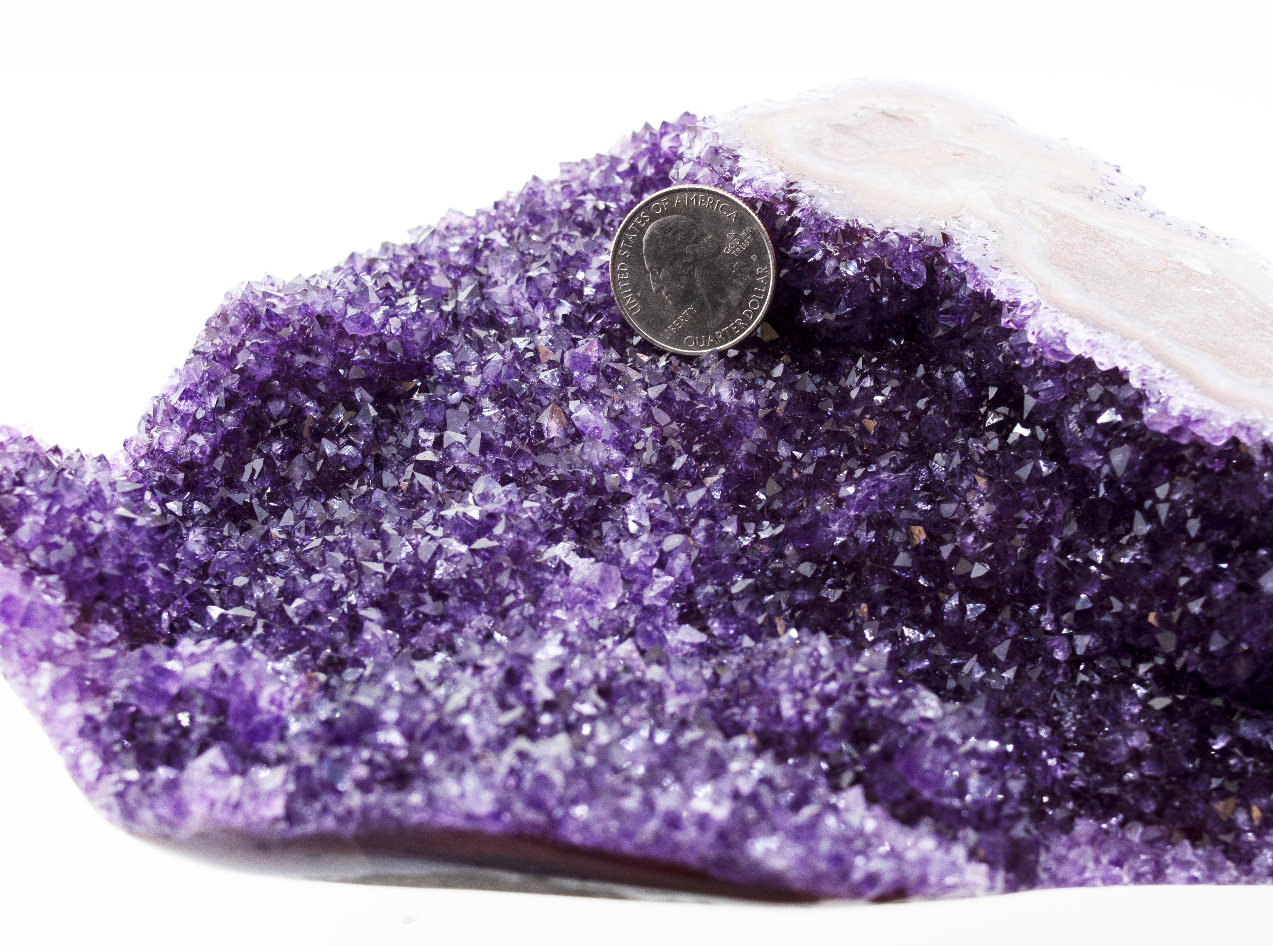 A decorative Beautiful Freeform Amethyst Geode with a coin on top.