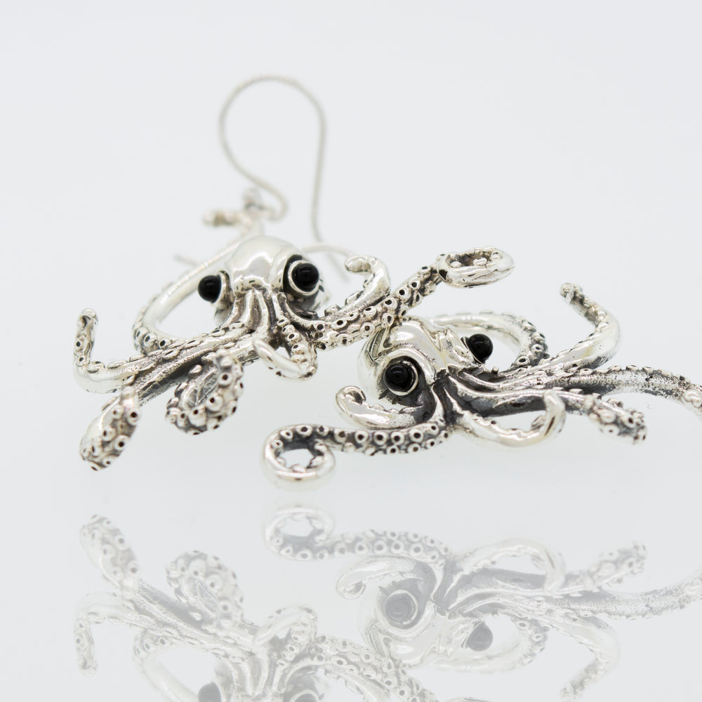 A Super Silver pair of Designer Octopus Earring with Onyx Eyes on a white surface.