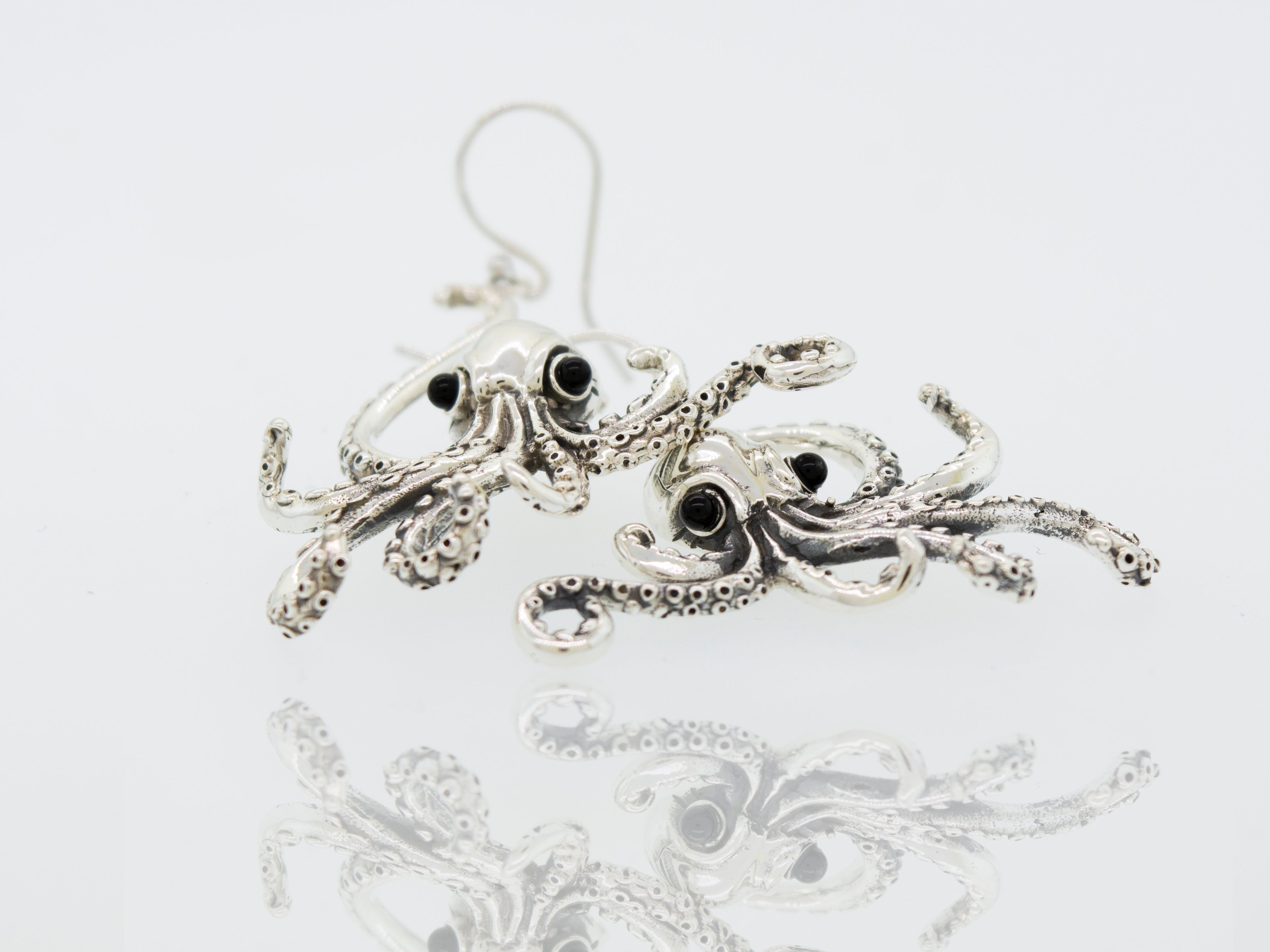 A Super Silver pair of Designer Octopus Earring with Onyx Eyes on a white surface.