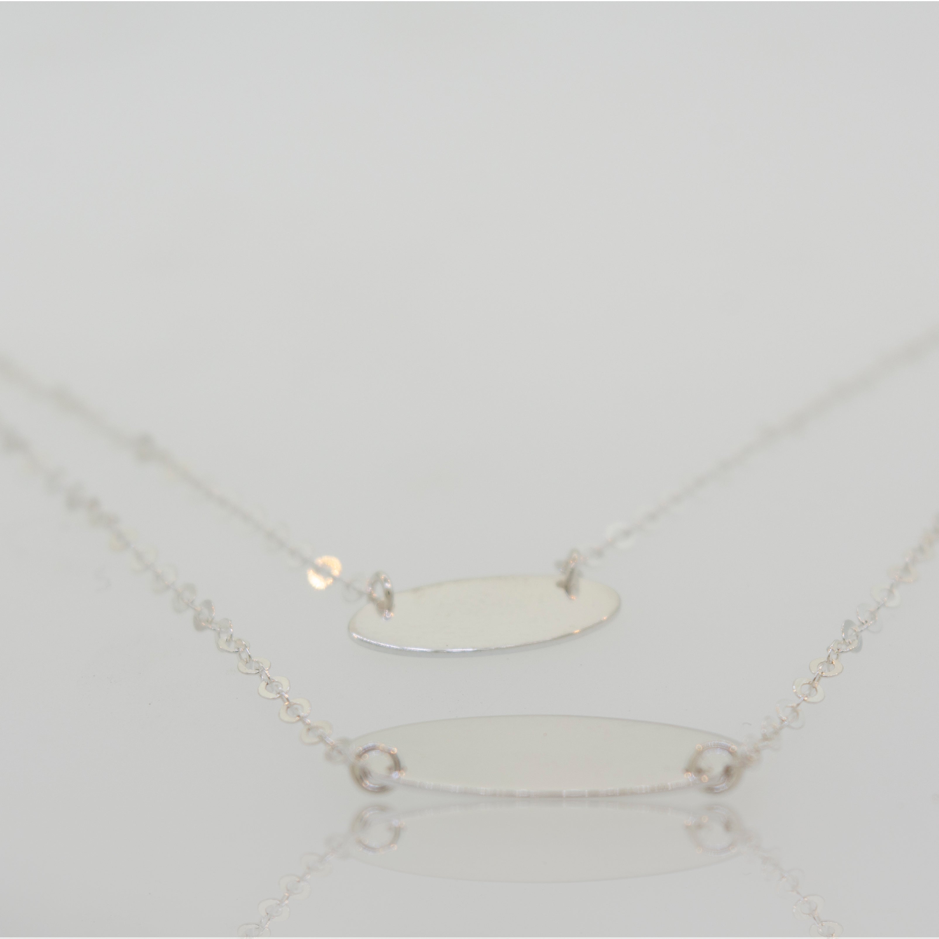 Two Elegant Sterling Silver Necklaces with Oval Disc Pendants by Super Silver on a white surface.