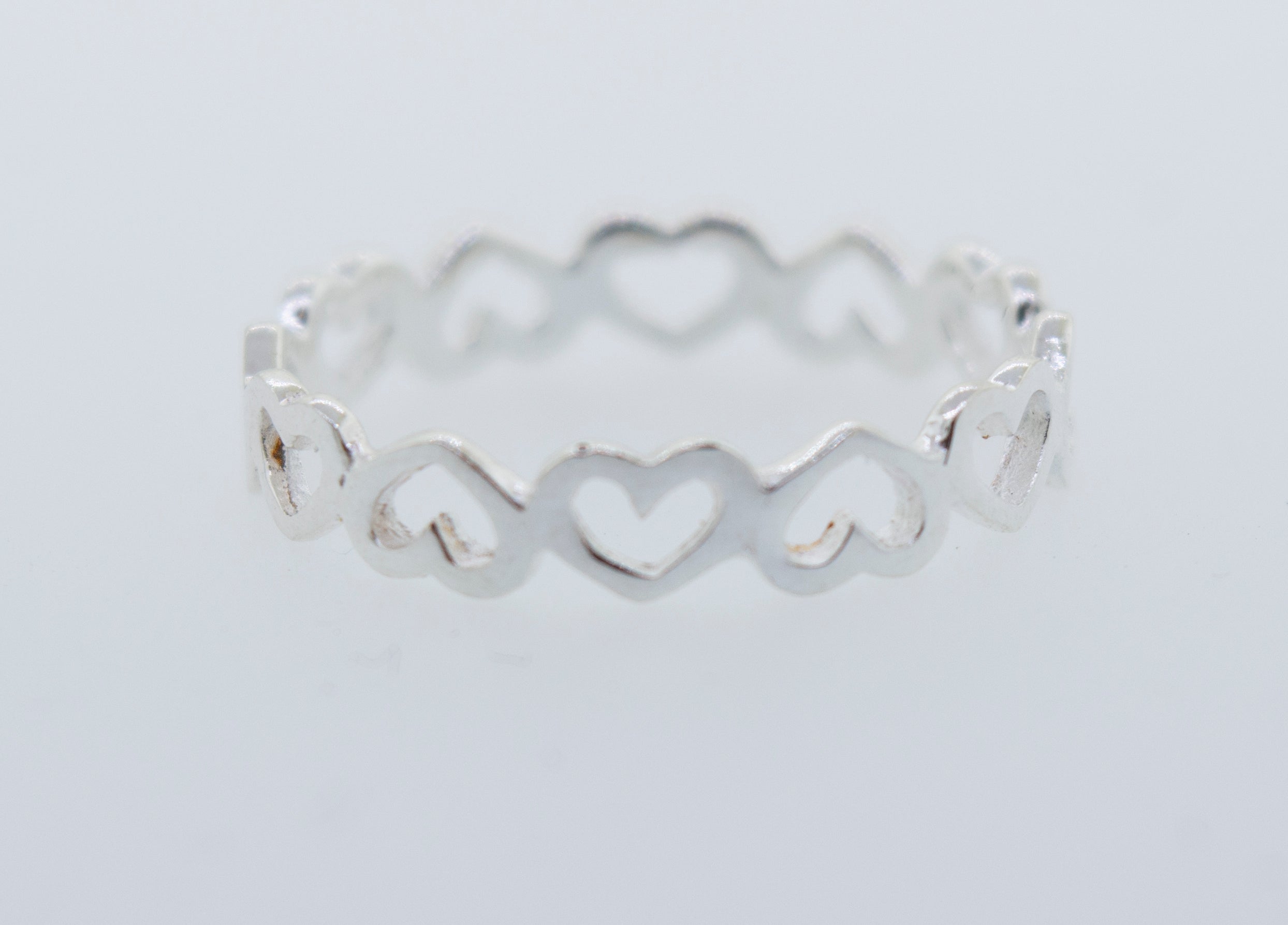 A minimalist Open Heart Band Ring with hearts on it.