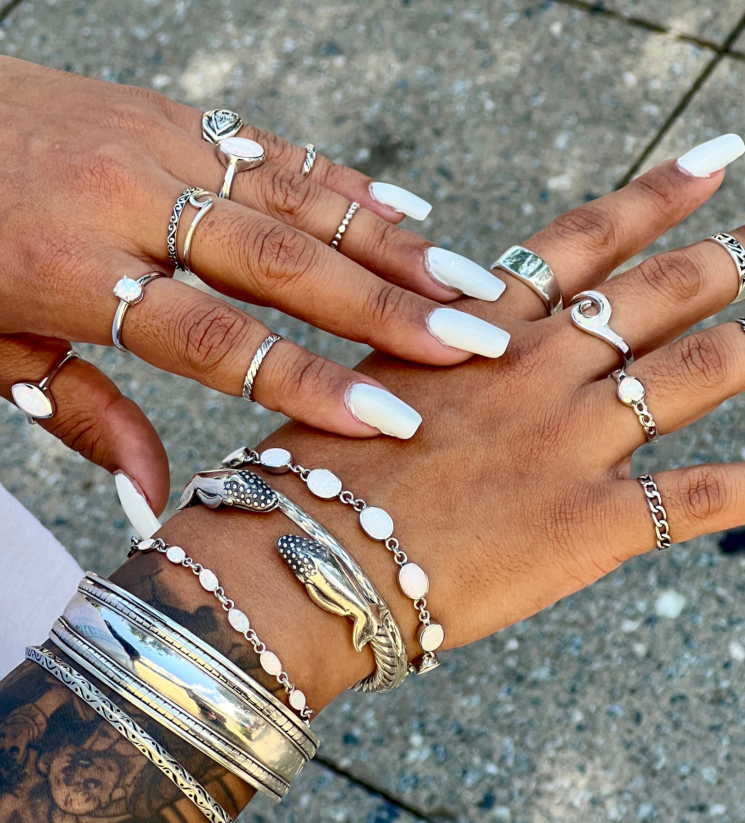 A woman's hands adorned with Super Silver's Exquisite Whale Hinge Bracelet, evoking the tranquil beauty of the ocean in Santa Cruz.