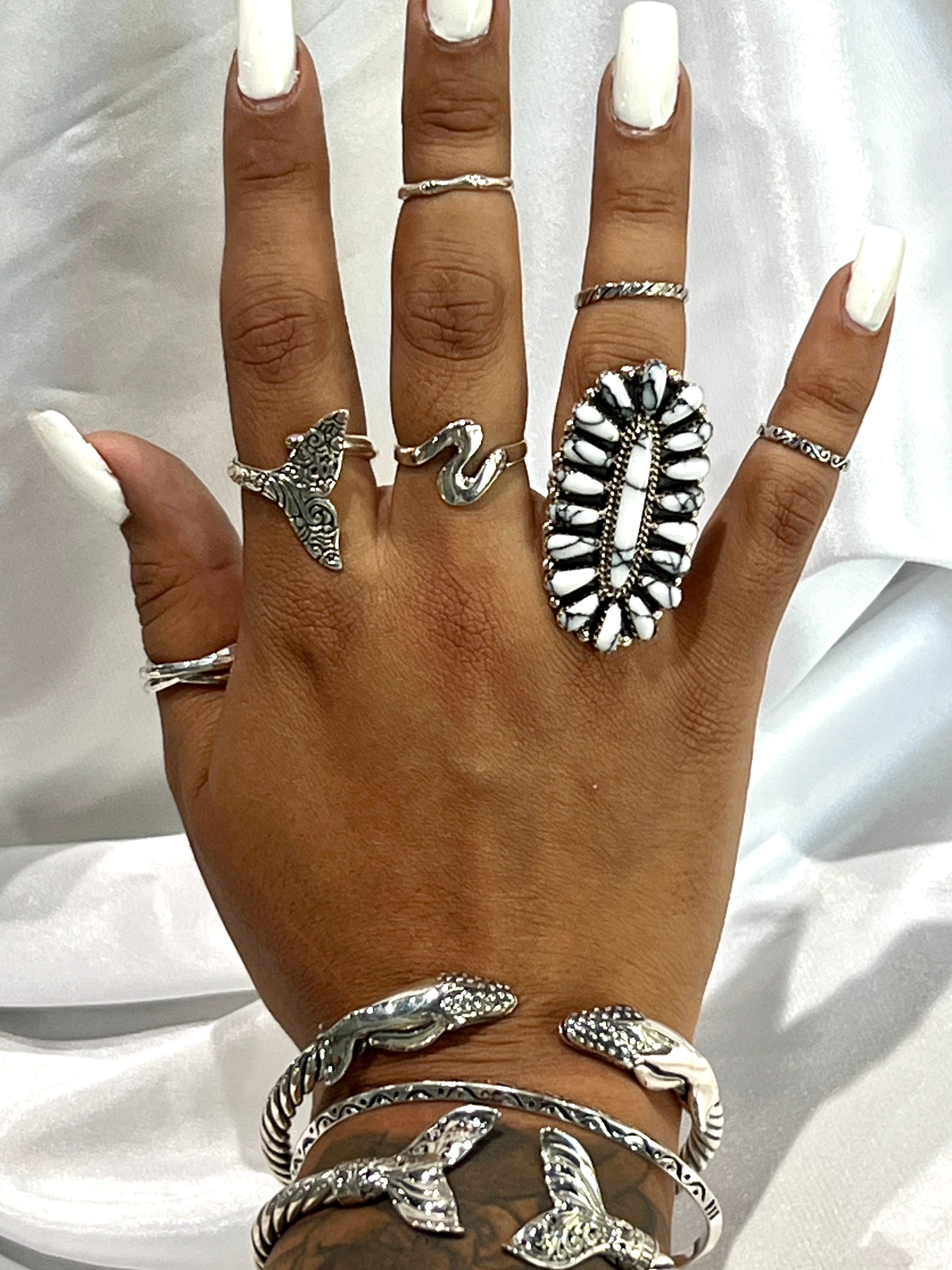 A woman's hand adorned with Super Silver's Exquisite Whale Hinge Bracelet, reminiscent of the tranquil ocean vibes of Santa Cruz.