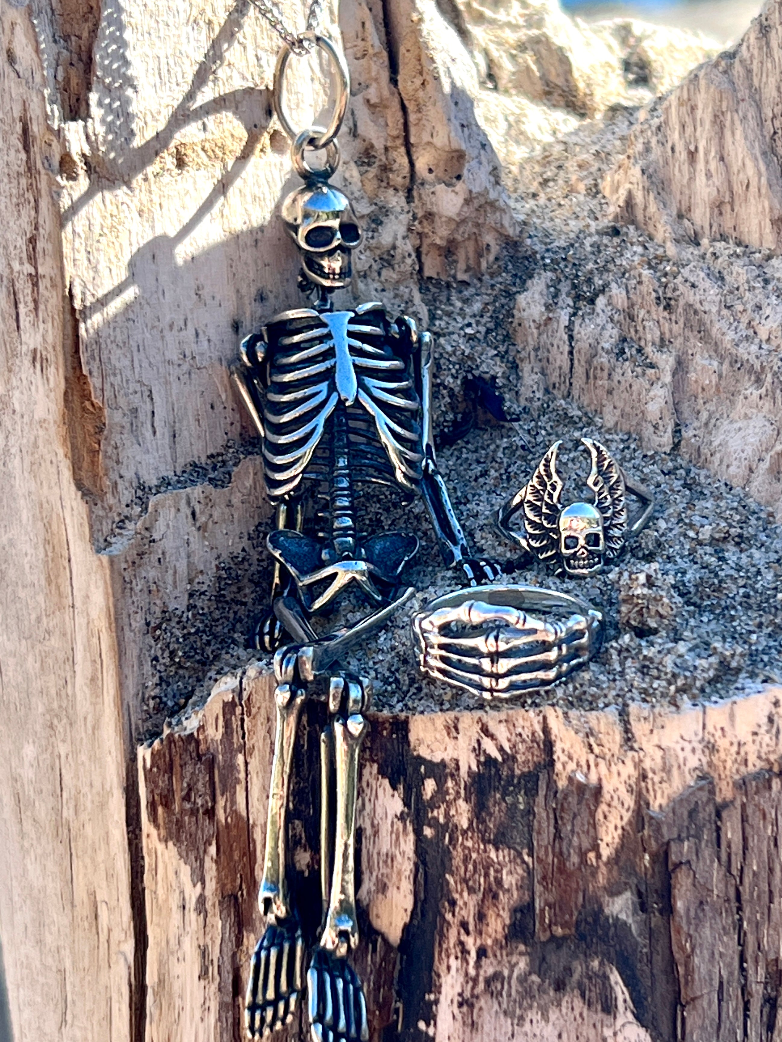 A Super Silver Large Skeleton Pendant sits on a statement piece of wood, showcasing its unique style.