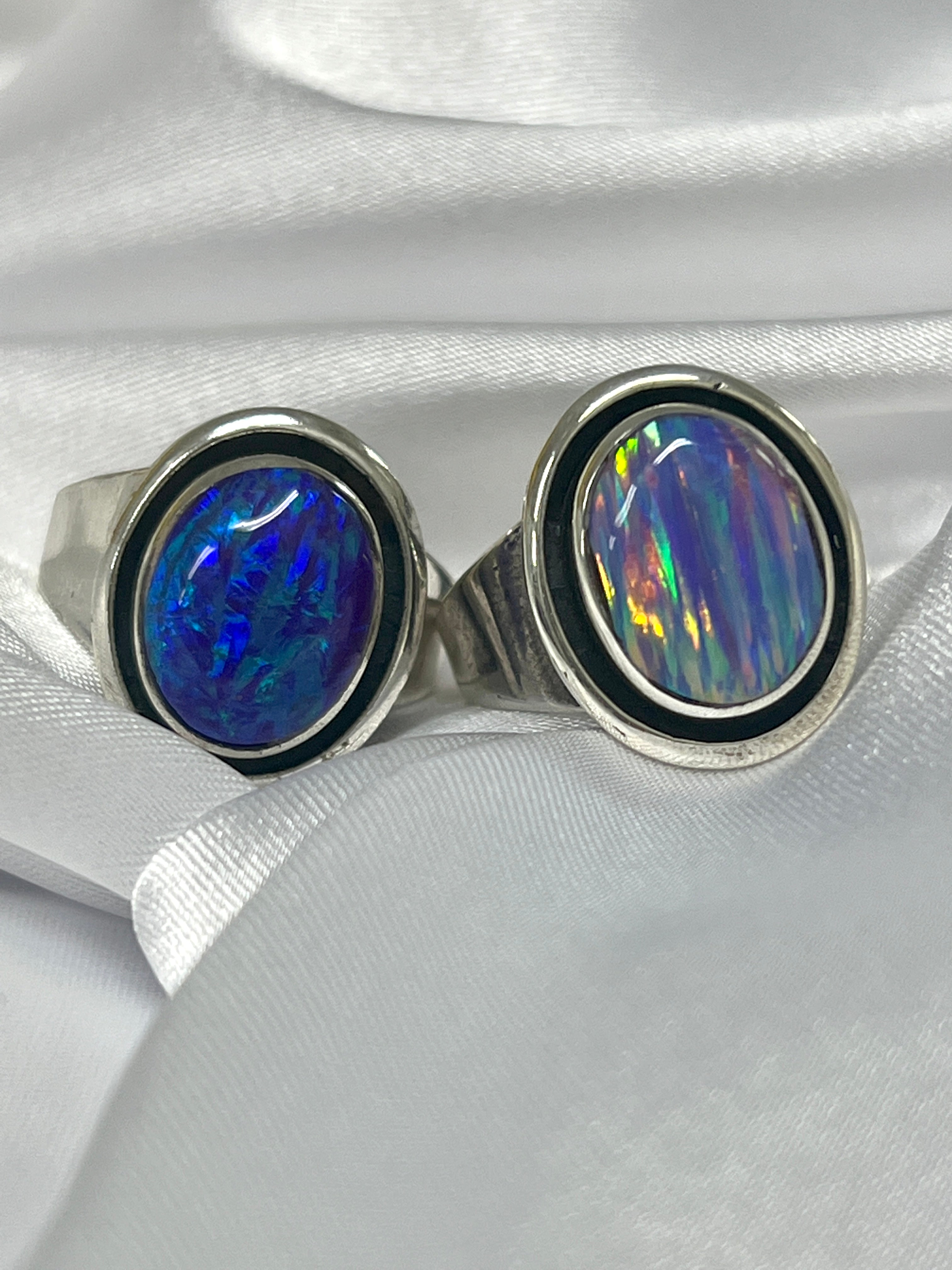 Two Radiant Opal Signet Rings on a white cloth.