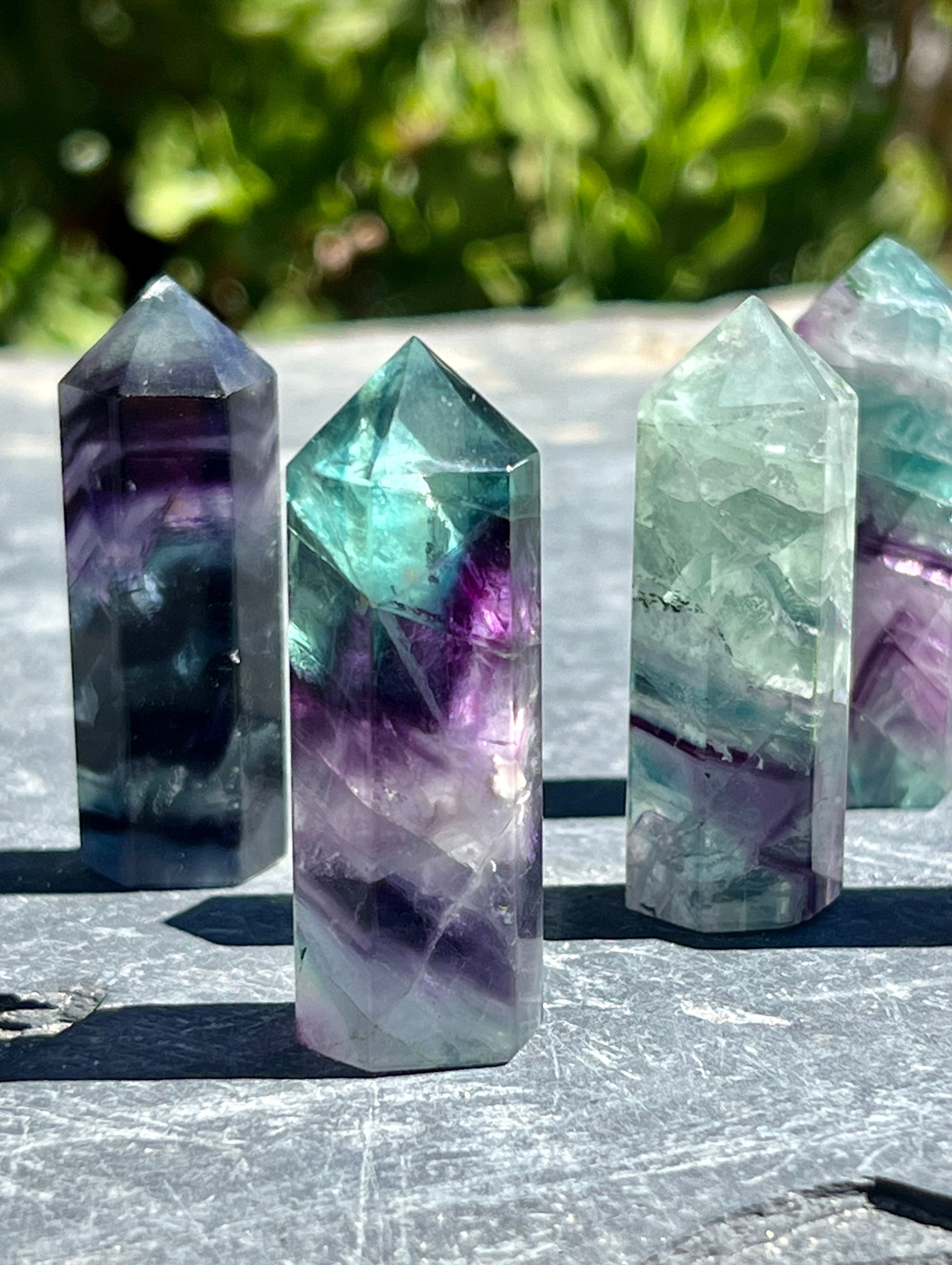 Four Rainbow Fluorite Obelisks on a table.