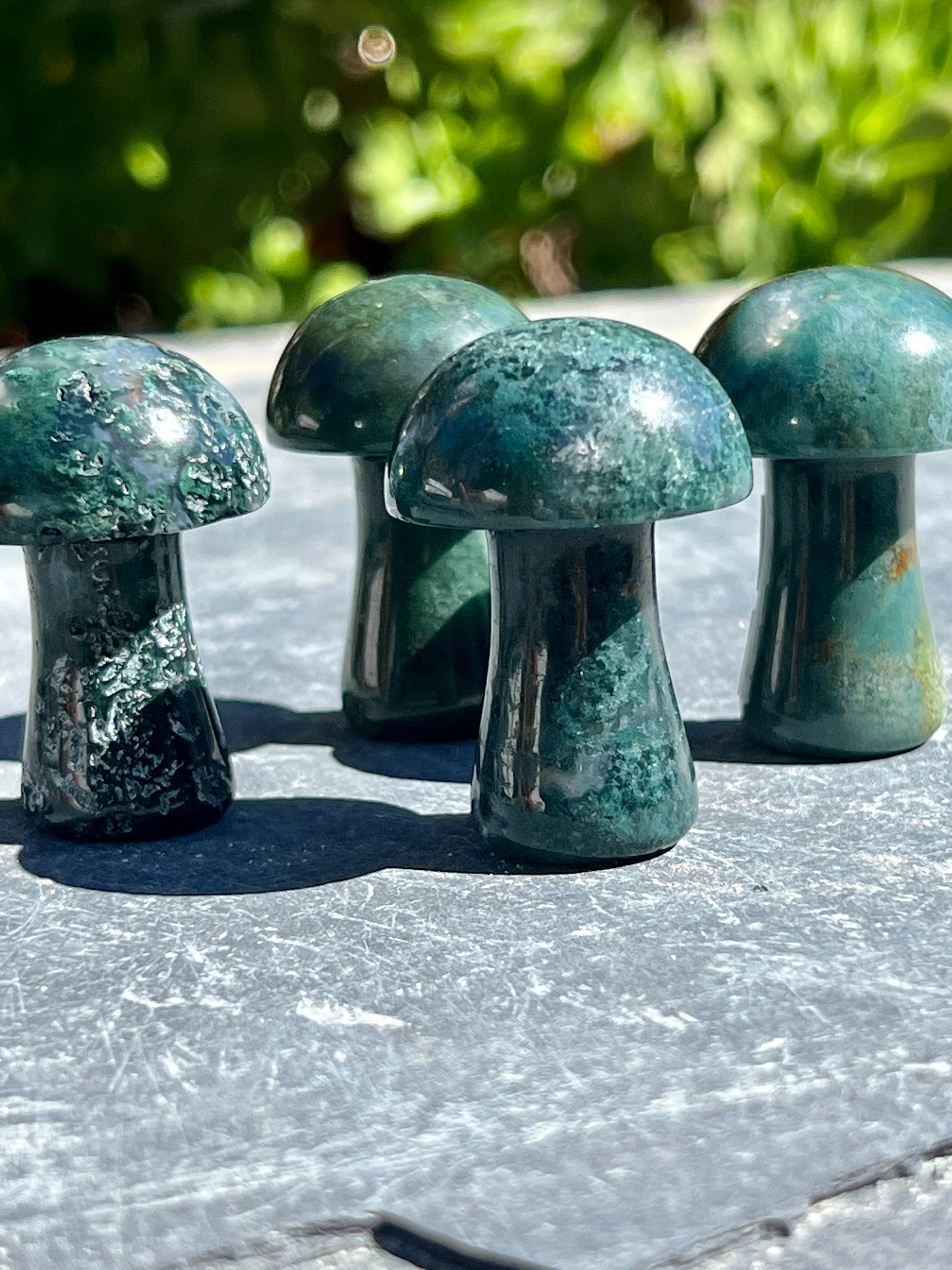 Three Moss Agate Mushroom stones on a table.