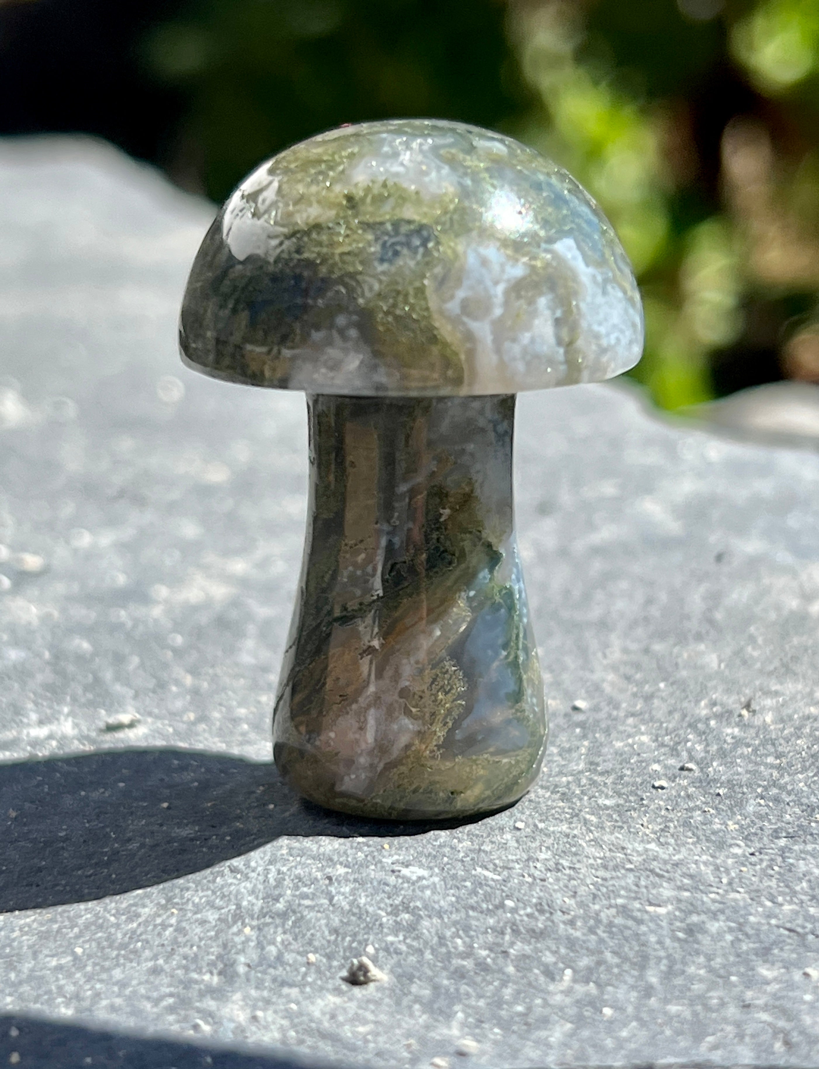 A small Moss Agate Mushroom sitting on top of a stone, serving as a unique decor piece.