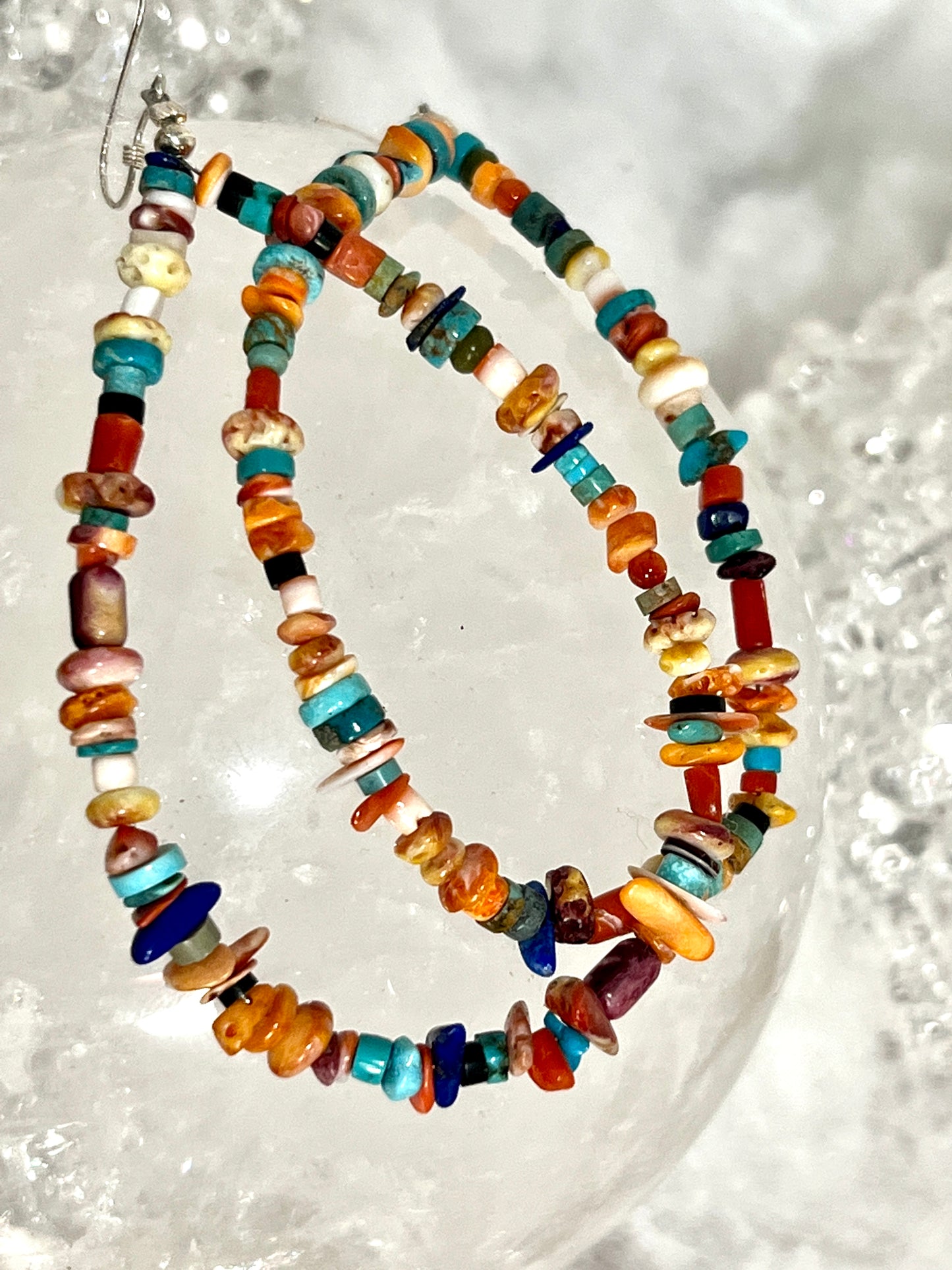 A pair of Brilliant Southwest Beaded Earrings from Super Silver, in southwest sunset colors, adorned with colorful beads, showcased on top of ice.