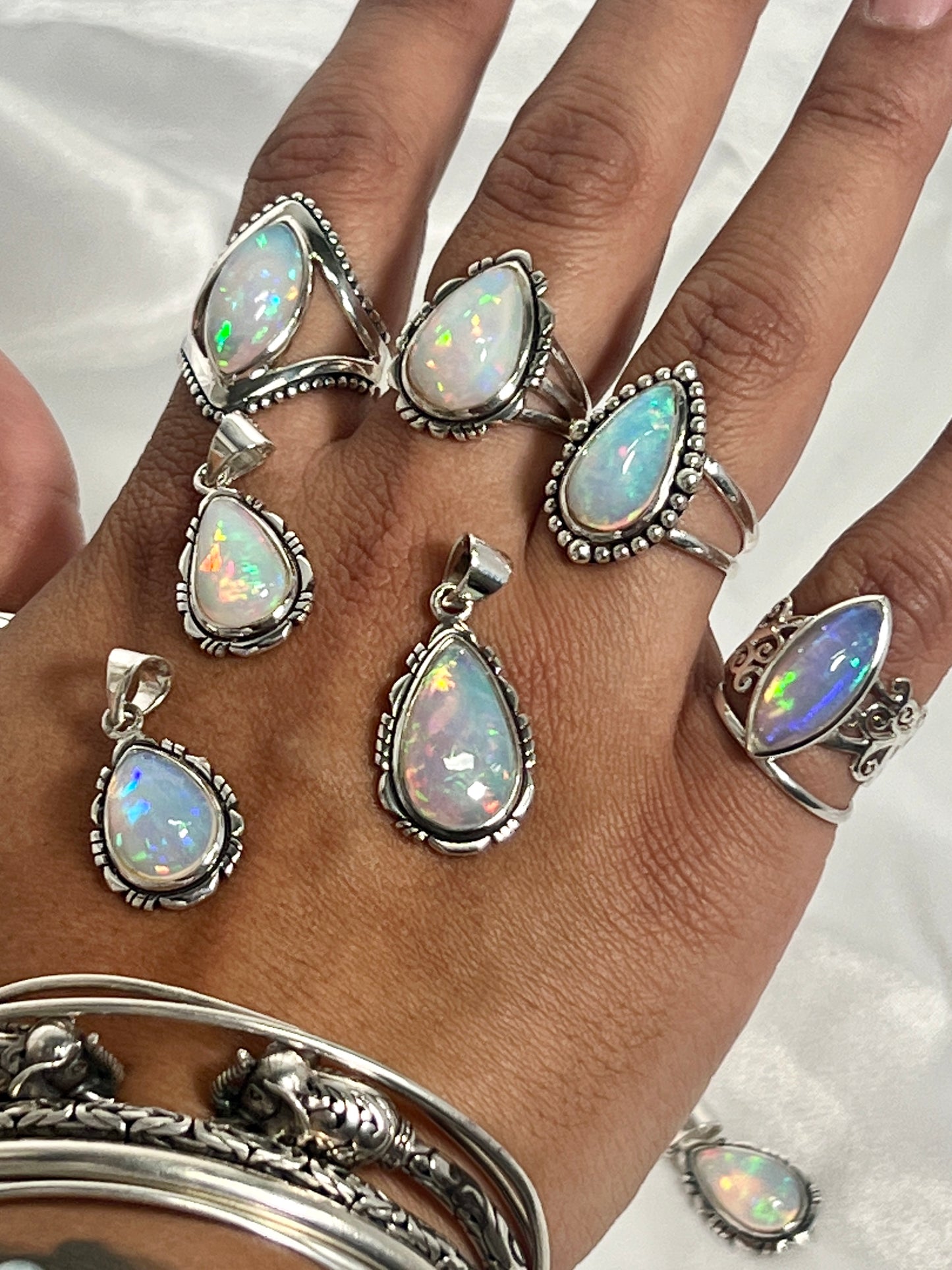 
                  
                    A woman's hand adorned with a stunning Super Silver Ethiopian Opal Teardrop Shaped Pendant with Detailed Setting, a true statement piece of jewelry.
                  
                