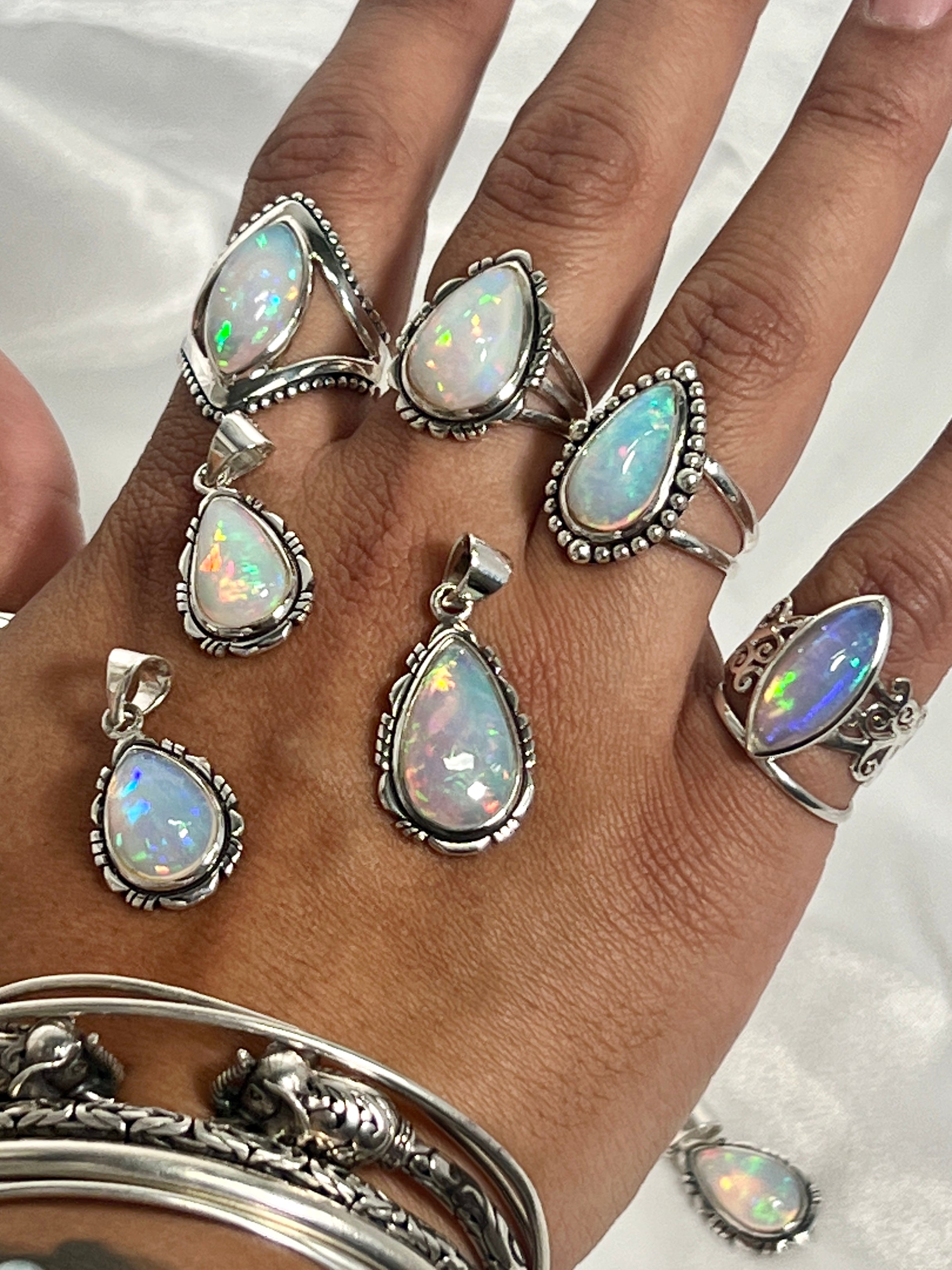 A woman's hand adorned with a stunning Super Silver Ethiopian Opal Teardrop Shaped Pendant with Detailed Setting, a true statement piece of jewelry.
