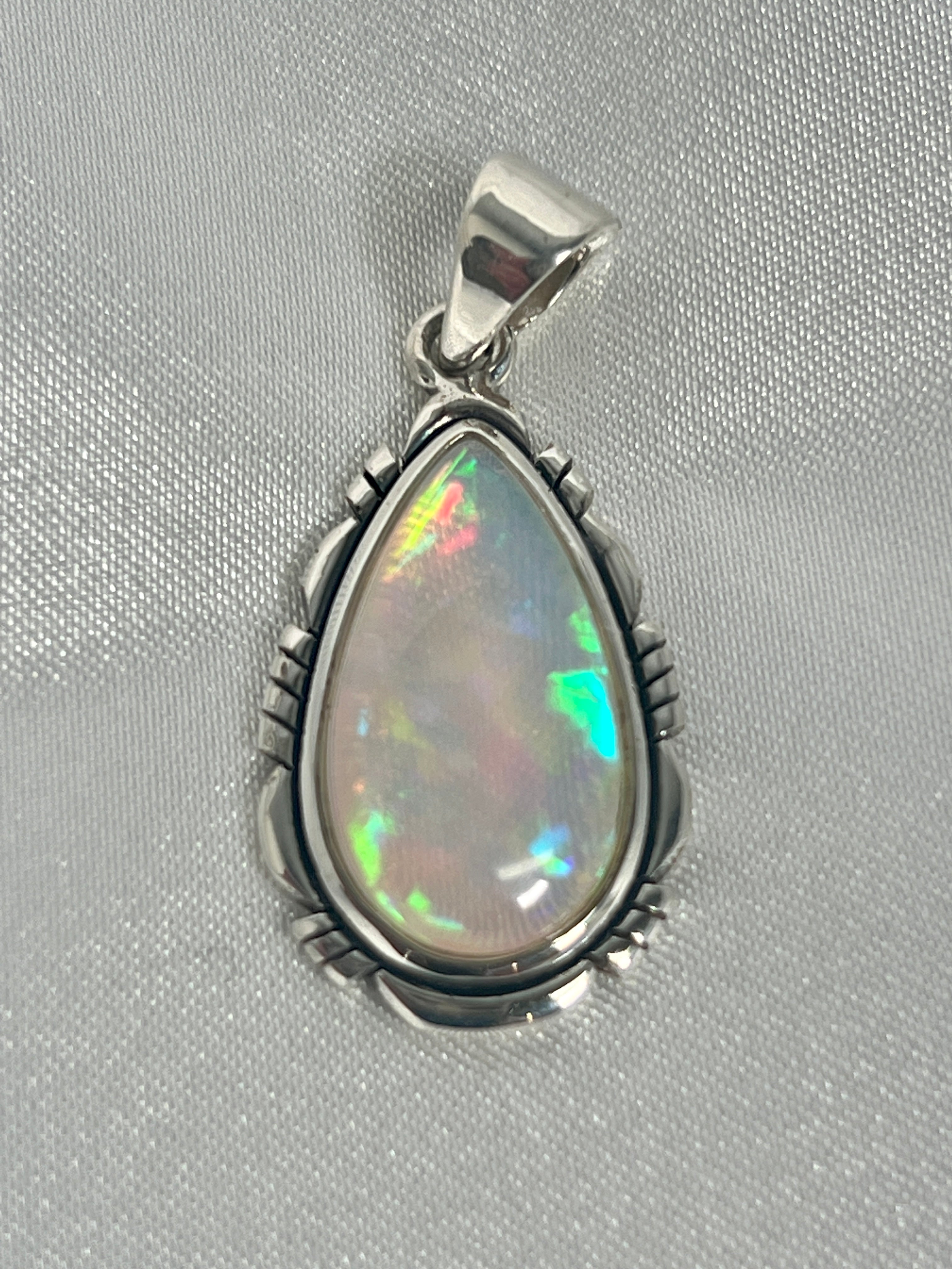 A Super Silver statement pendant featuring a brilliant Ethiopian Opal Teardrop Shaped Pendant with Detailed Setting, set in sterling silver.
