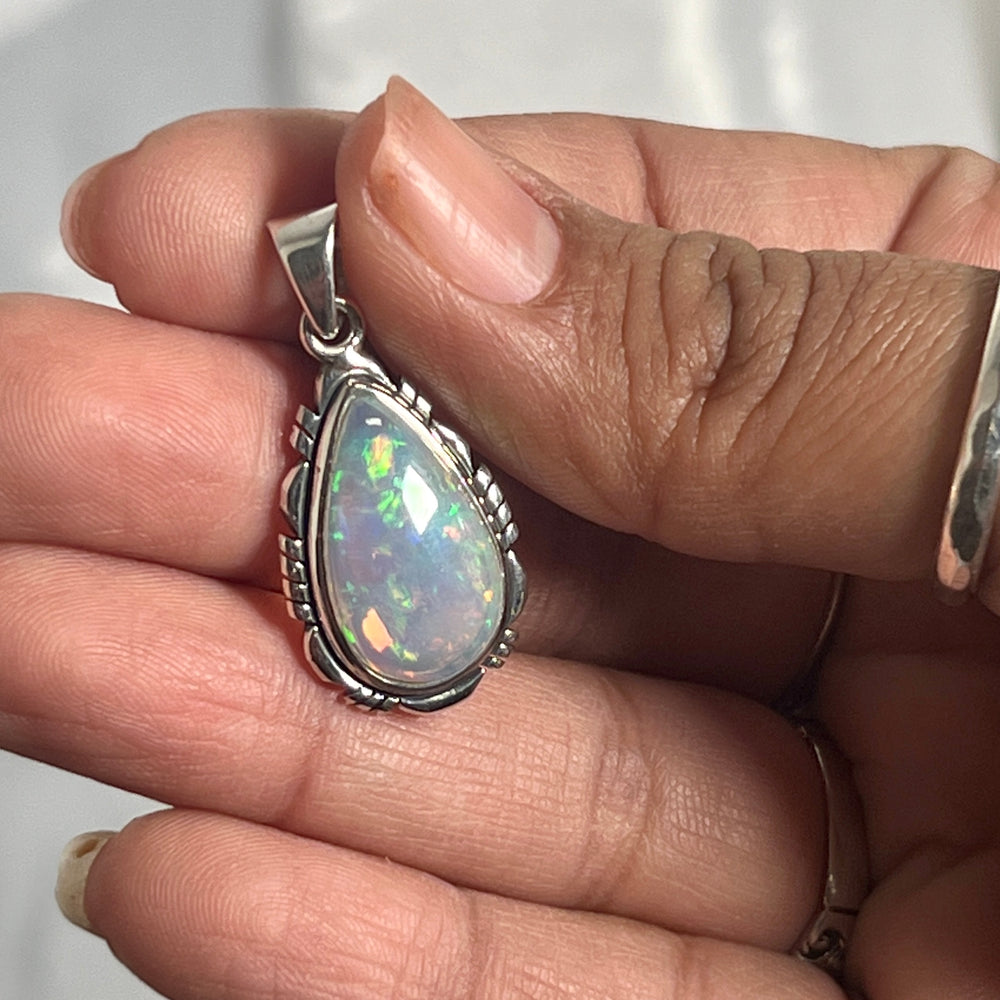 
                  
                    A person gracefully holding a Super Silver Ethiopian Opal Teardrop Shaped Pendant with Detailed Setting, accentuating its brilliance as a captivating statement piece.
                  
                