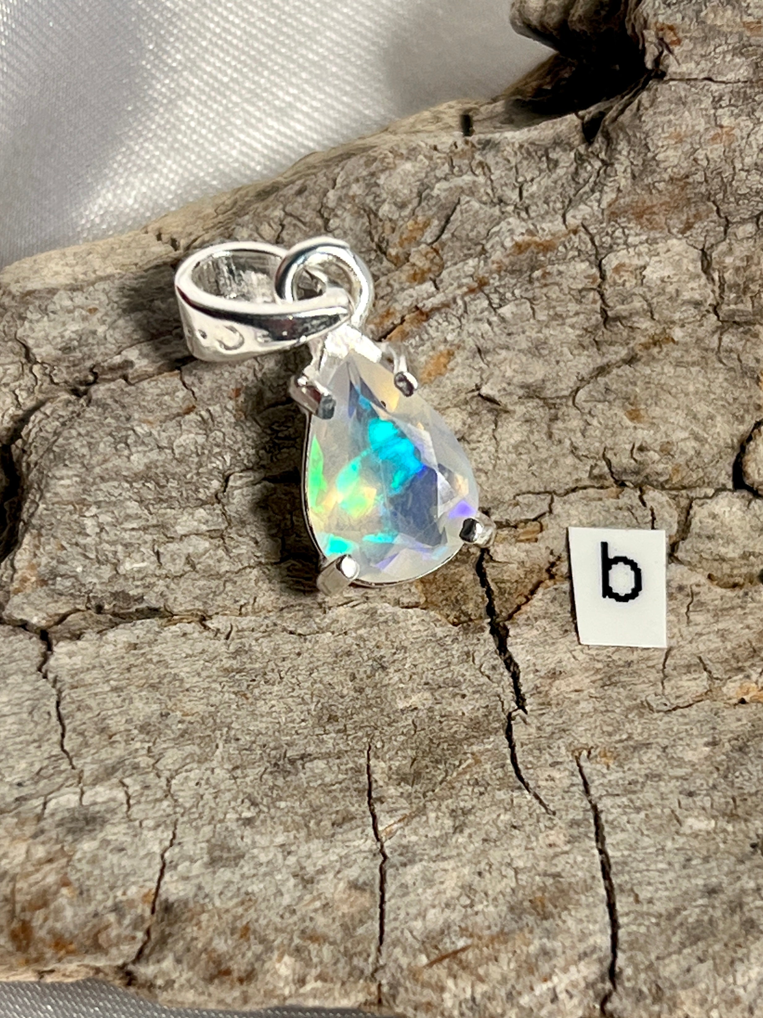 A Dainty Prong Set Facet Cut Teardrop Shaped Ethiopian Opal Pendant with the letter b on it, crafted in Sterling Silver by Super Silver.