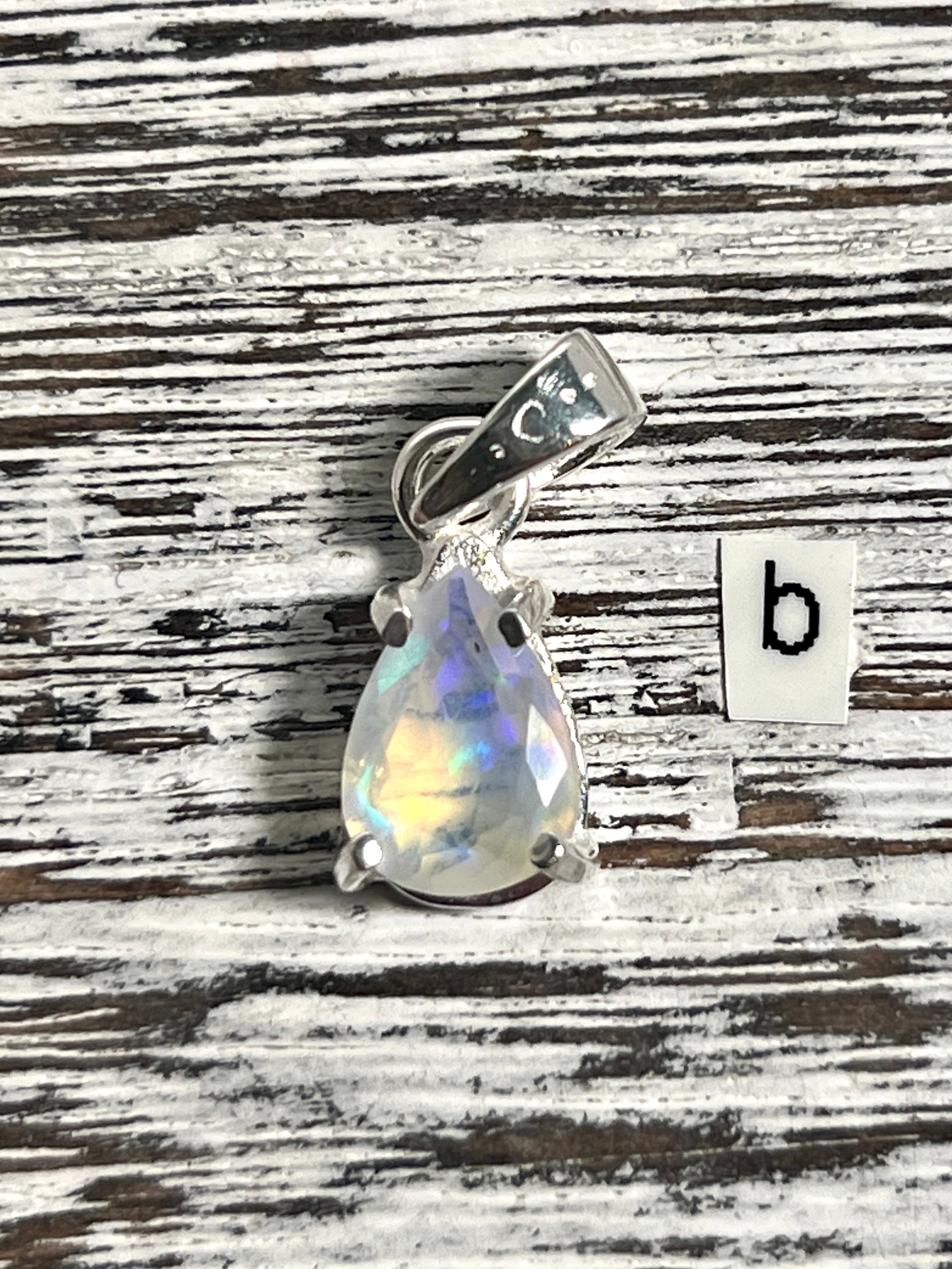 A Super Silver Dainty Prong Set Facet Cut Teardrop Shaped Ethiopian Opal Pendant with the letter b.